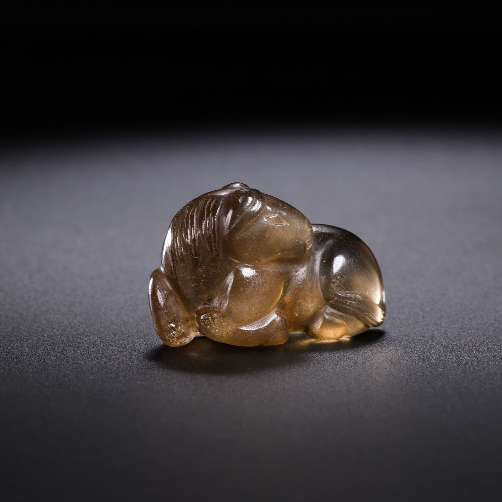 A RARE AND EXQUISITELY CARVED ROCK CRYSTAL FIGURE OF A RECUMBENT HORSETANG DYNASTY OR LIAO/JIN: DescriptionThe miniature figure is masterfully carved from a single block of translucent, high-clarity rock crystal. It depicts a horse in a restful recumbent position, with its legs tucked neatly ben