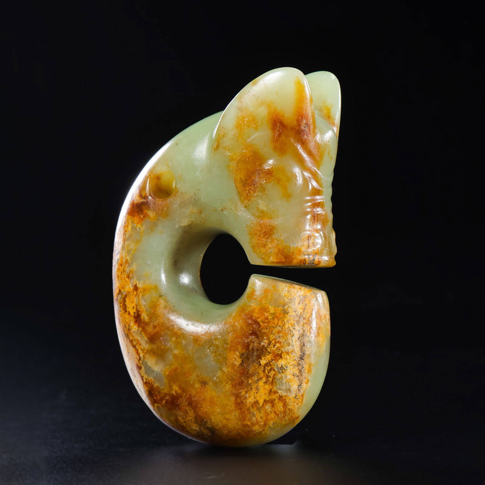 A RARE YELLOW JADE 'PIG-DRAGON' (ZHULONG)HONGSHAN CULTURE, NEOLITHIC PERIOD (C. 3500-3000 BC): Description The deity-form ornament is robustly carved from a translucent yellowish-celadon jade with extensive natural russet coloration (qinse). The 'Pig-Dragon' is depicted in its quintessential co