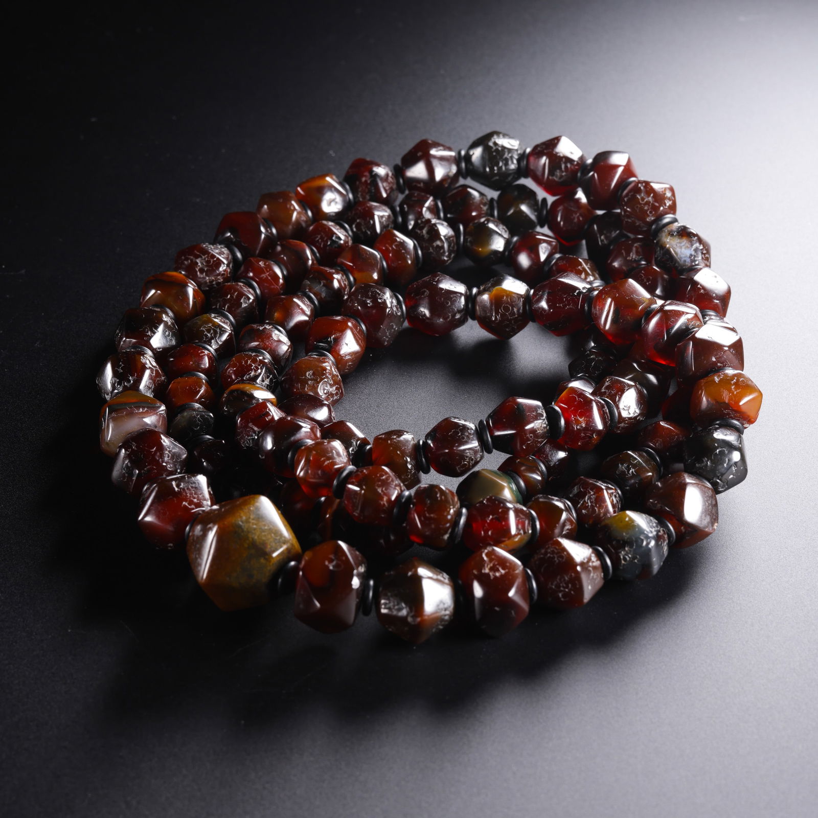 A RARE AND MAGNIFICENT AGATE BEADED NECKLACETANG DYNASTY (618–907 AD): The necklace is composed of a series of meticulously polished agate beads of varying sizes, featuring a prominent, large central bead. The agate is of exceptional quality, displaying a rich, transluce