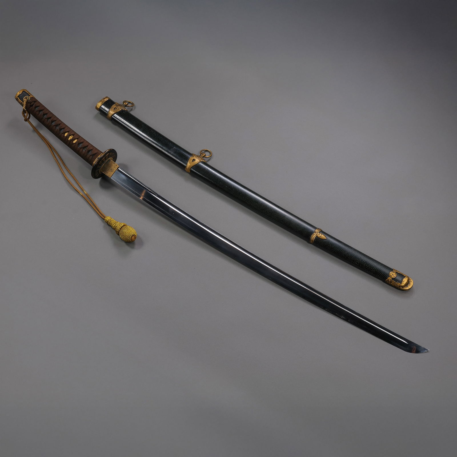 AN IMPRESSIVE GILT-MOUNTED 'KATANA' WITH FAMILY CRESTS (MON)EDO PERIOD (17TH–19TH CENTURY): Description This monumental and elegantly appointed Katana (Long Sword) is a quintessential example of the refined military aesthetics of the Edo Period. The sword is complete with its full mountings