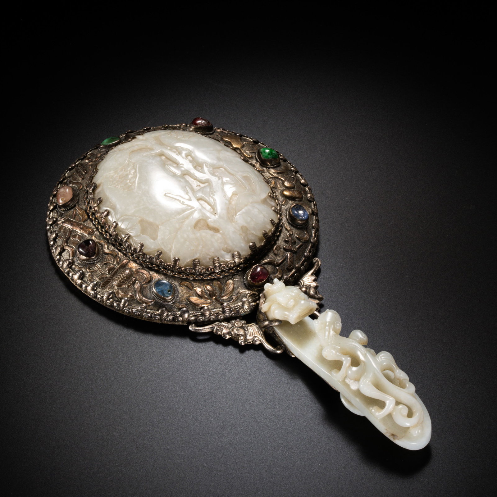 Chinese Qing Dynasty Hetian white jade, silver-plated, gemstone-inlaid hand-held mirror: H . 20 cm . W . 10.9 cm . Weight 214 gram .