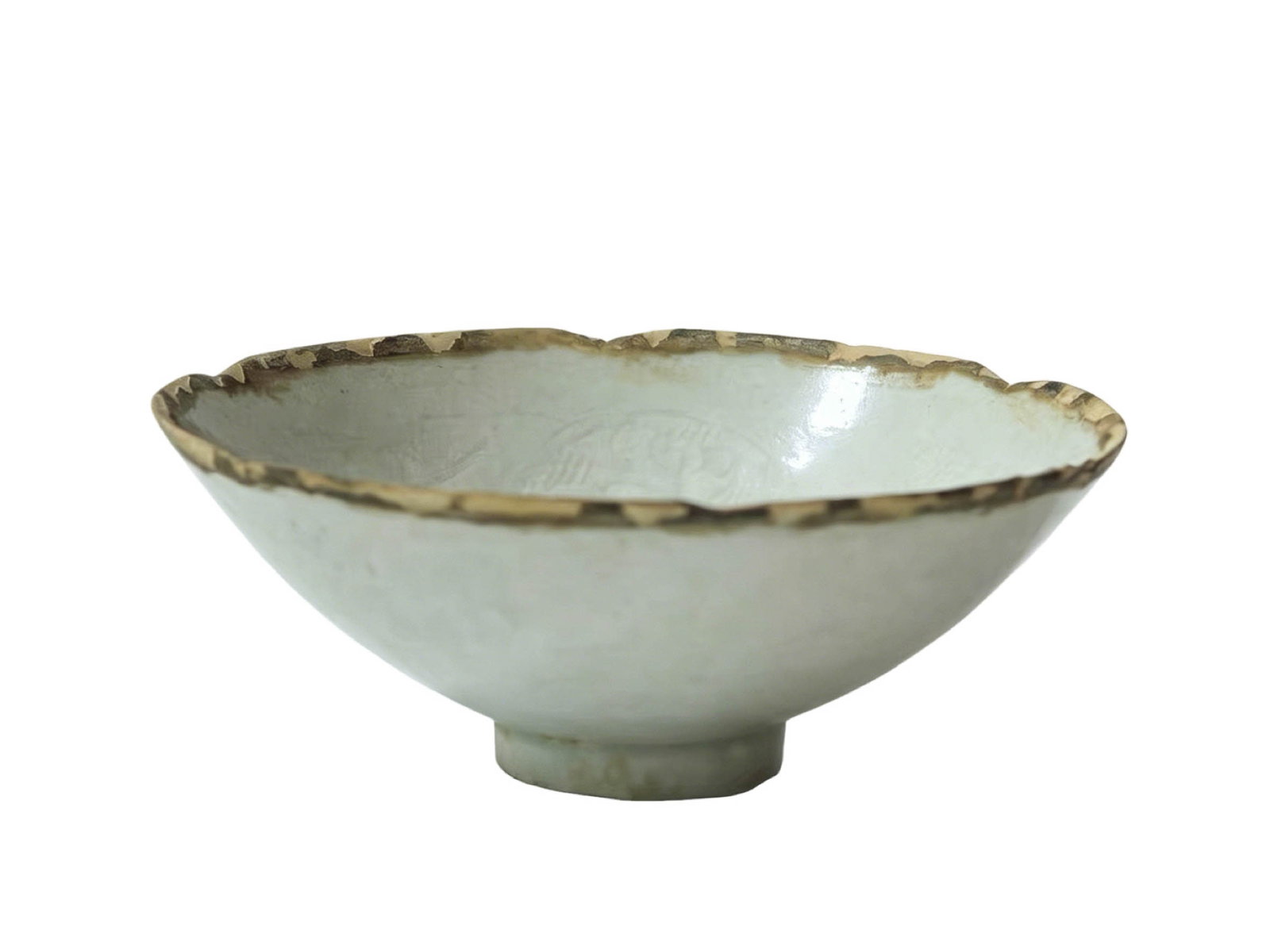Conical tea bowl with six-lobed floral rim, carved phoenix medallions and shadow celadon glaze,: The vessel is fully intact without any restoration; part of the original silver edging around the rim still remains attached, and there is a tiny chipping mark on the base left when the piece was