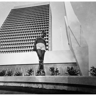 Paul Kodjo (1939-2021, Côte d'Ivoire/Ghana) Fashion editorial shot in front of the: Paul Kodjo (1939-2021, Côte d'Ivoire/Ghana)Fashion editorial shot in front of the Stabilization Fund building, Plateau, Abidjan, 1970Silver print, 2019Signed, dated "Paul Kodjo 2019" on the