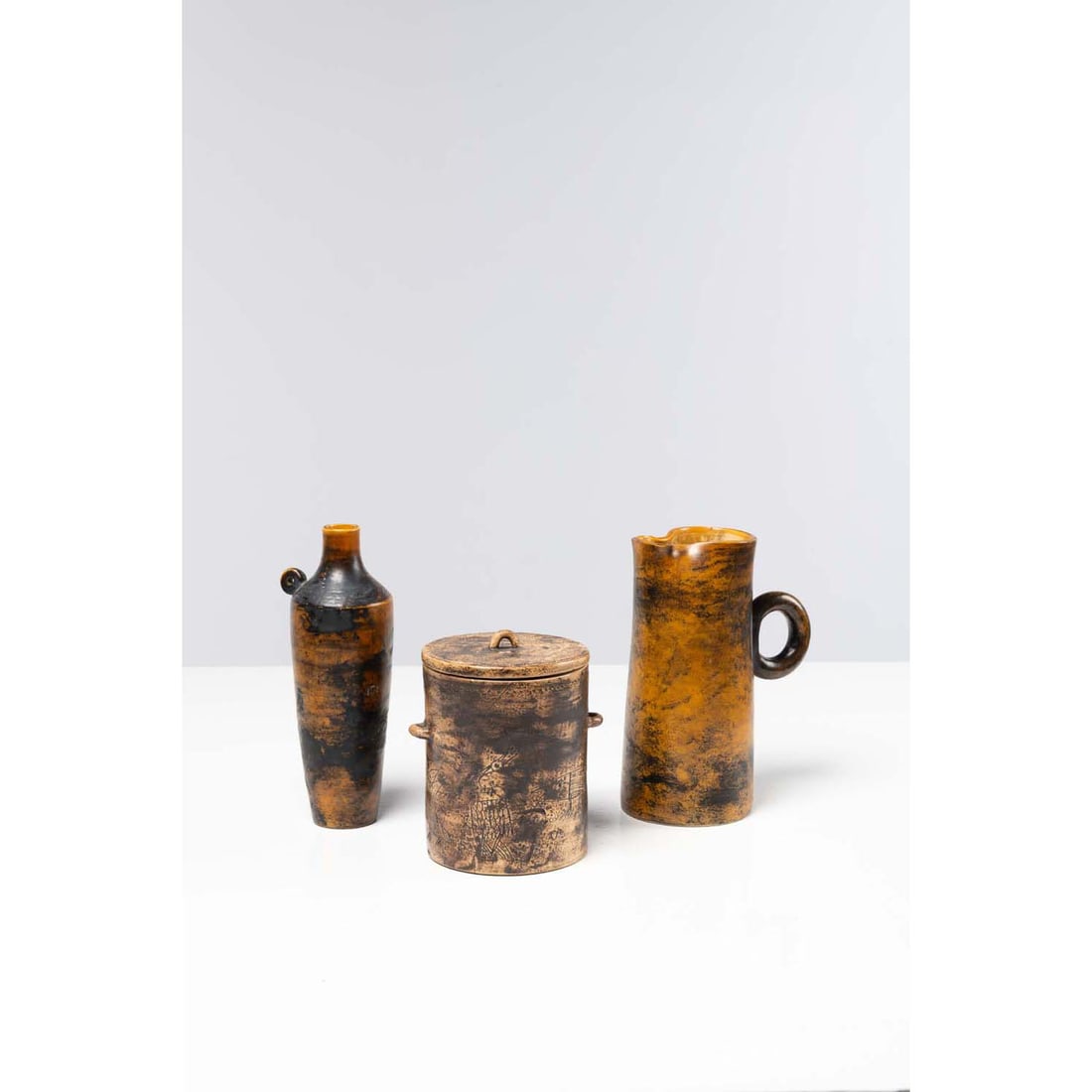 Jacques Blin (1920 - 1995) Set comprising a jug, a covered pot and a vase with handle: Jacques Blin (1920 - 1995)Set comprising a jug, a covered pot and a vase with handleGlazed ceramicSigned 'J. Blin' under the baseCreated around 1960 H 22 x Ø 7 cm (vase)H 20 x W 15 x D 9.5 cm (pi