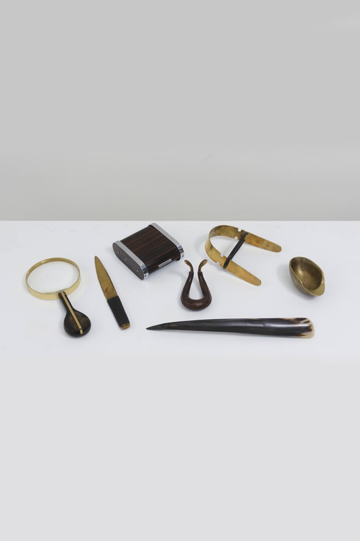 Carl Auböck (1900-1957) Set of elements with: ashtray '3597', letter opener: Carl Auböck (1900-1957)Set of seven elements with: ashtray '3597', letter opener'4236', magnifying glass, bottle holder'4260',cigarette case, pipe stand and shoehornBrass, leather, horn, bronze, wood