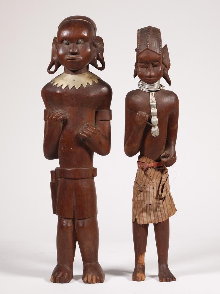 (2) AFRICAN WOODEN FIGURES: 20th c. Maasai (Masai) carved hardwood figures of a Warrior and Wife, with typical elongated ear lobes, the man missing his shield and spear, having a carved belt with knife in sheath; the woman in co