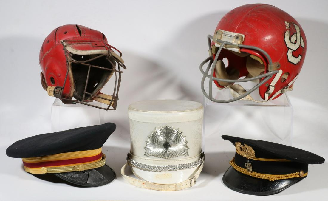 (5) COLLEGE HELMETS & BAND HATS: Early Football Helmet (University of Cincinnati?); Red Leather Cricket Helmet; White Drum Majorette Helmet, (2) Marching Band Billed Caps, military style. Some mold, damage to bill of one cap.