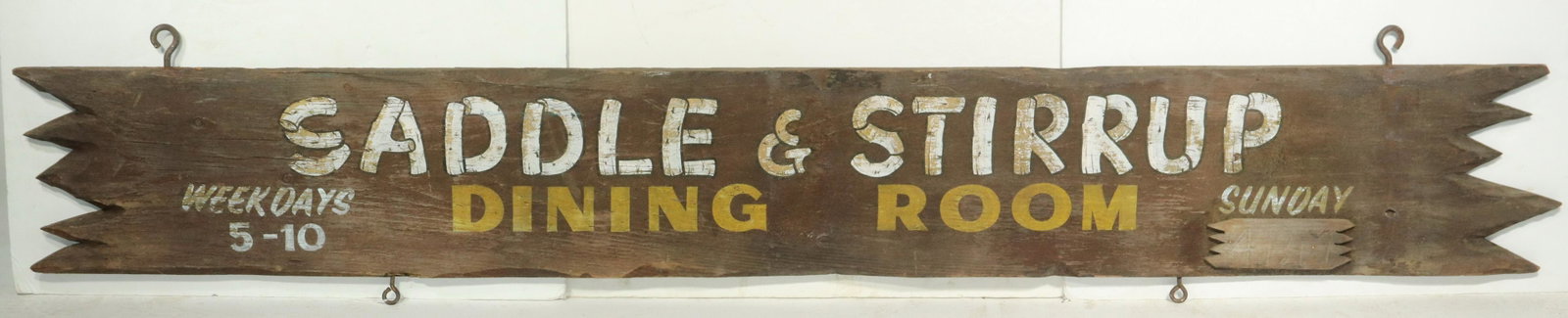 RUSTICATED EXTERIOR SIGN: Painted Pine Sign "Saddle and Stirrup Dining Room, Weekdays 5-10", rough sawn, with sculpted "Old West" ends, 11 1/2" x 81". Weathered.