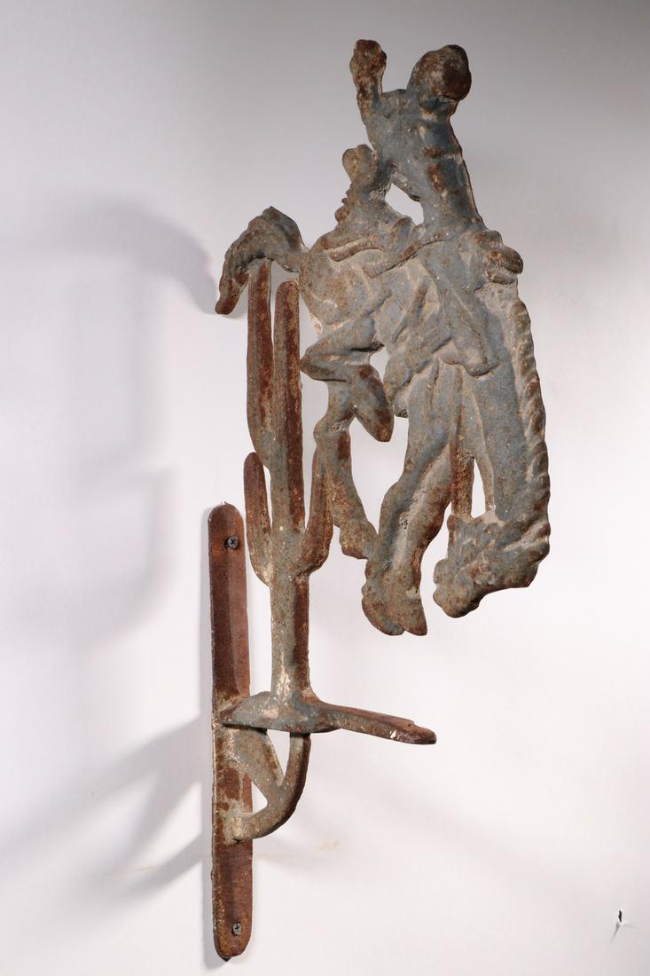 IRON BUCKING BRONCO WALL BRACKET: Vintage Cast Iron Cowboy and Bucking Horse Wall Mount Bracket, with cactus, once a holder for a bell, 22" high, 11 1/4" x 1 1/4". Weathered surface with rust.