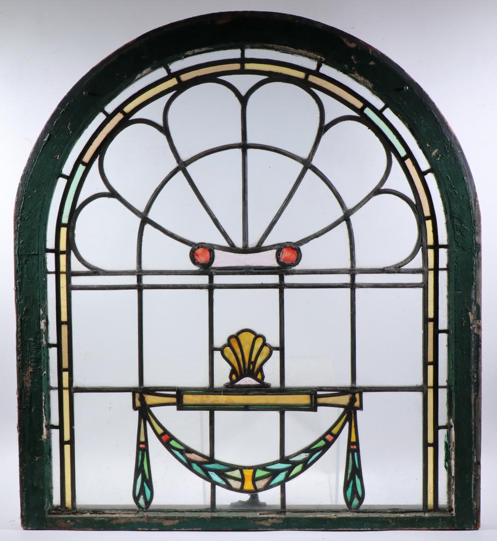 TOMBSTONE SHAPED STAINED GLASS WINDOW: Simple Leaded Glass Neo-Classical Design in a green painted wooden frame, having set into clear glass a colored band, Doric column, shell, baton and swagged greens, 37 1/2" x 33 3/4" x 1 3.4". Slotted