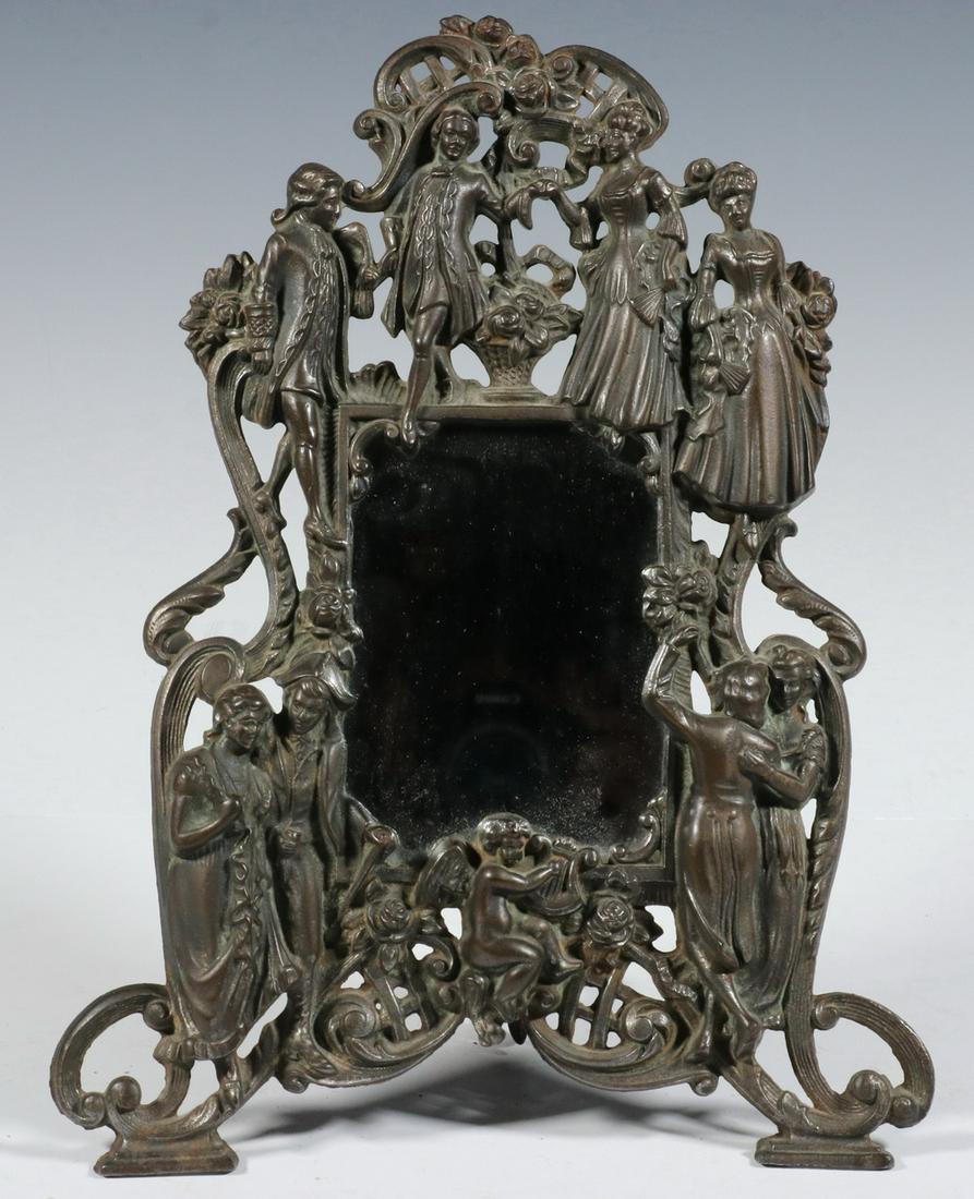 VICTORIAN IRON FIGURAL TABLE MIRROR: Late 19th c. Cast Iron Framed Mirror, depicting images of couples in a variety of period attire, cupid at the base, with hinged stand, 14 1/4" high, 10 3/4" wide. Mirror is a replacement.