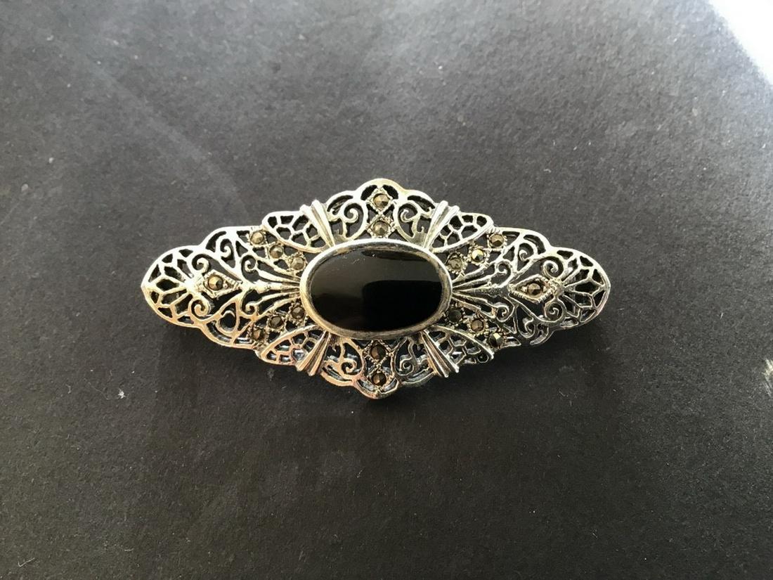 STERLING BROOCH: Vintage Sterling Silver Reticulated Brooch, set with marcasite stones and an oval black onyx center stone, 2" long. Fine condition.