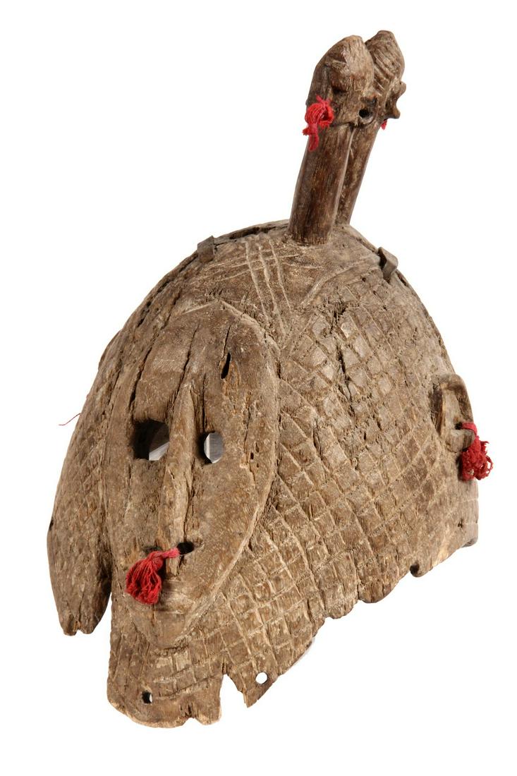 AFRICAN MASK: Mende Ceremonial Helmet Mask with Janus heads, representing Sowo, the water spirit and used in a female ritual, having remnants of red cloth tassels, Nigeria, early 19th c., 14" x 11" x 8 1/2". Old st