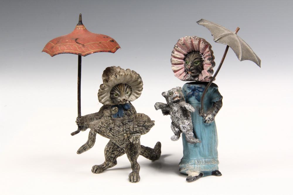 (2) AUSTRIAN FIGURES: Two Cold Painted Figures of Mother Cats carrying Kittens, one in dress is bronze, both in bonnets and holding parasols, cat in dress has a nodder head is made of lead, both about 4" tall. Good conditi