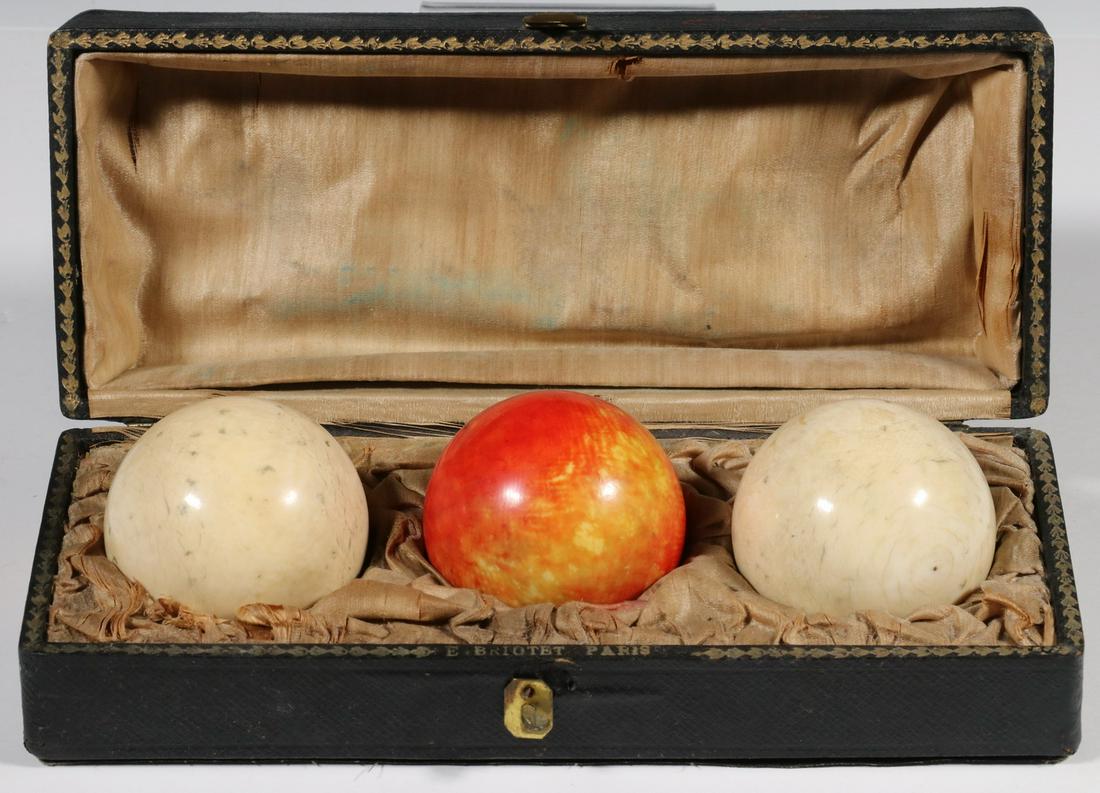 UNUSUAL SET OF (3) CUE BALLS IN ORIGINAL FITTED BOX: 19th c. French Cue Balls for Billiards, one stained red, the silk lined fitted case is marked "E. Briotet, Paris", the balls are 2 1/2" diam., the case is 3" x 9" x 3 3/4". Wear to red ball, latch bro