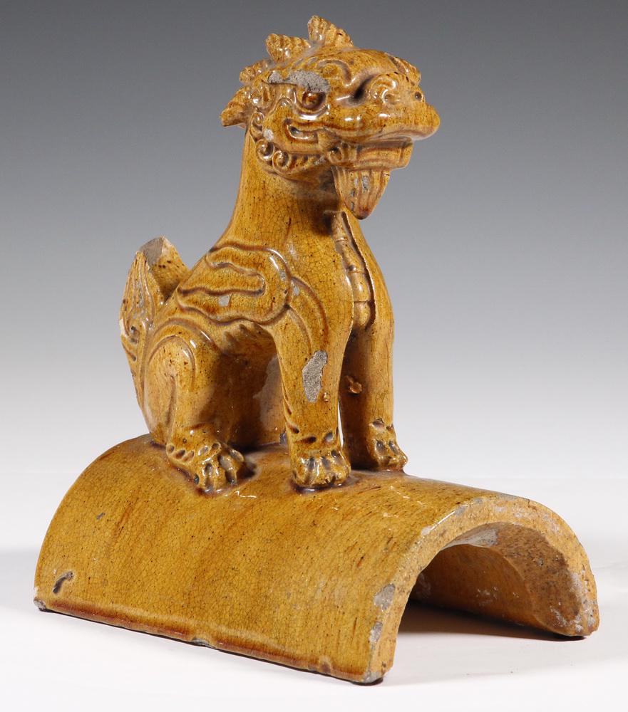 CHINESE QING GLAZED POTTERY ROOF TILE FINIAL: 19th c. Seated Foo Dog Acroteria in golden ochre sancai glaze, roughly 9" x 8" x 4 1/2". Good condition.