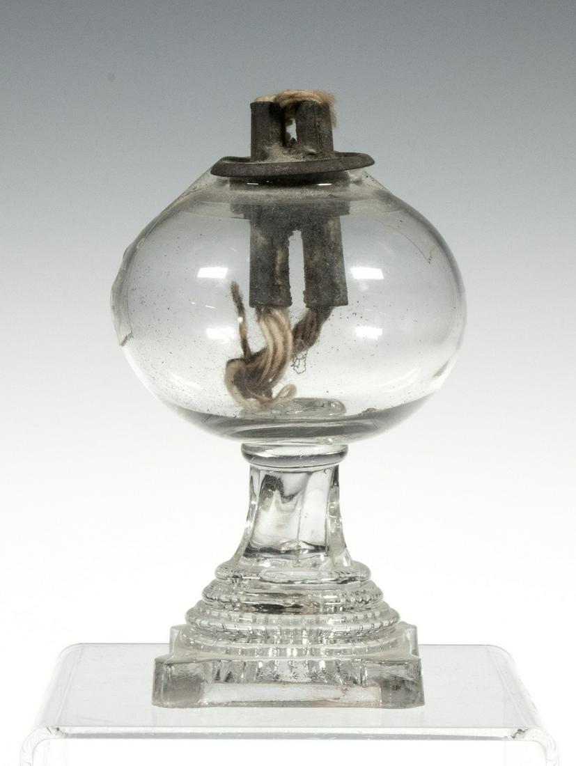 CLEAR GLASS WHALE OIL LAMP: 19th c. Free Blown and Pressed Glass Lamp, with globe font set on a pressed stepped and ribbed pedestal, square footed base with extended rounded corners, double tube burner, 4 1/2" high, 2 3/4" diam.