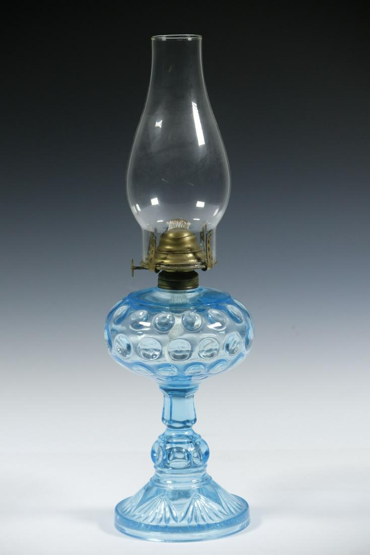 ANTIQUE BLUE GLASS OIL LAMP: Coin spot glass oil lamp with chimney. Burner component signed "Banner". 16 1/2" high. Small chips on inner side of base, otherwise good condition.