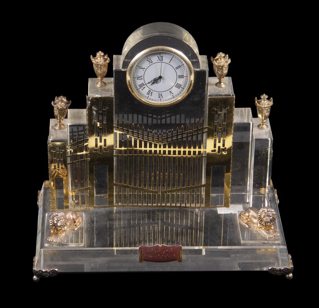 DESK CLOCK IN GATE FORM, GILT METAL & LUCITE: Plaque reads: "City of Ashraf" (Iraq), 6" x 8" x 4 1/2", one gilt urn off but present.