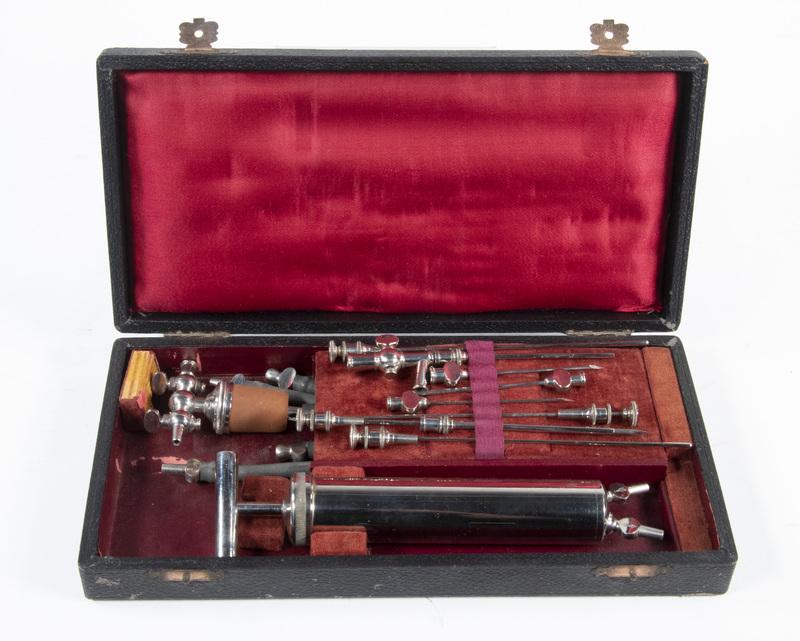 CASED MEDICAL ASPIRATION KIT: Circa 1900 Cased Set in chrome, with the pump, (8) needles, grey rubber hosing, valve sets with rubber stopper, in a black faux leather case with crimson silk fitted interior, 1 1/2" x 10 1/4" x 5". A