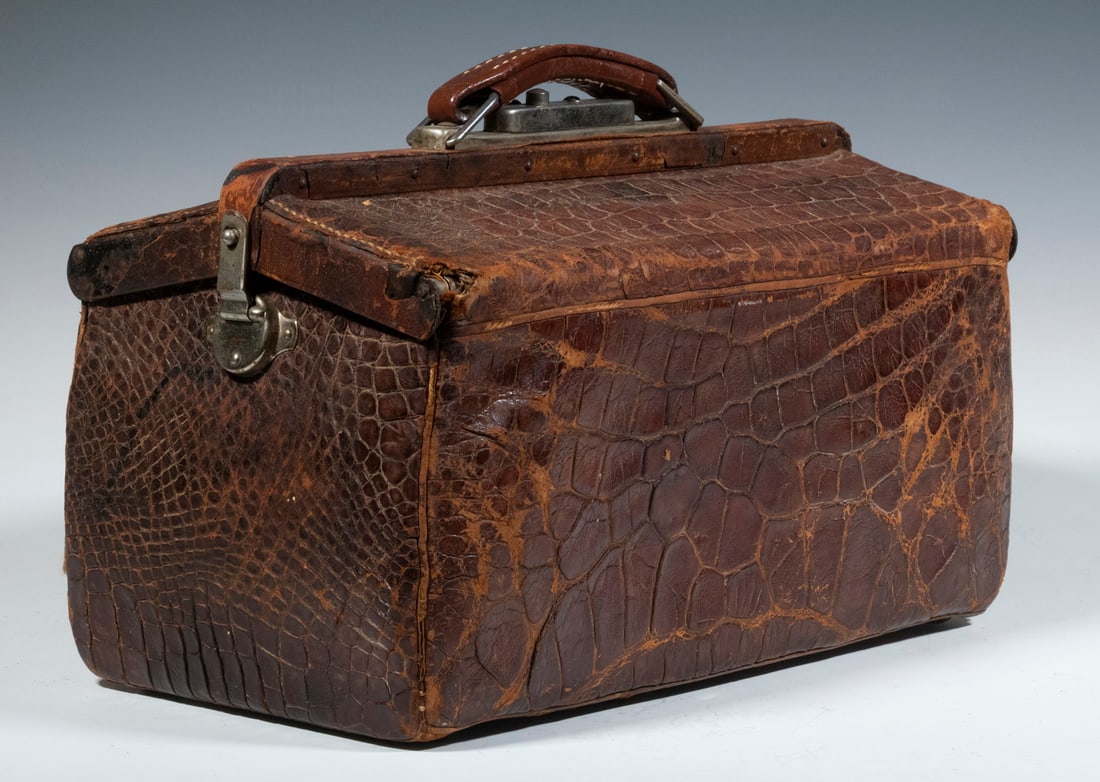 ALLIGATOR DOCTOR'S BAG: ALLIGATOR DOCTOR'S BAGEarly 20th c. Medical Bag, with alligator skin cover, double top flaps that open, side clasps and top push button latch, leather lined interior, 9 1/2" high, 14" x 7 1/2". Heavy