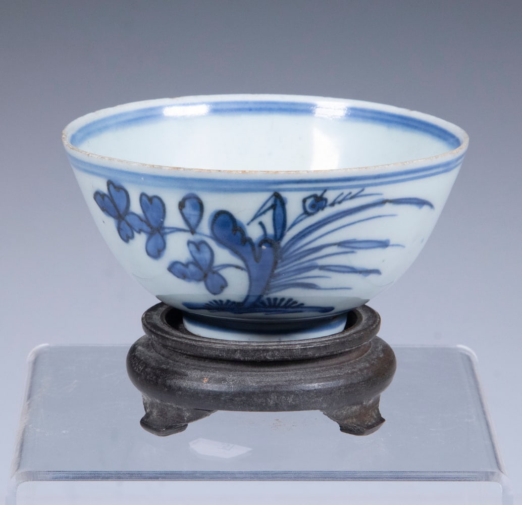 CHINESE PORCELAIN CUP: CHINESE BLUE AND WHITE PORCELAIN CUPBlue and White Footed Cup, with underglaze blue floral design, with wooden stand, 2" high, 4 1/4" diam. Minor roughness on top edge.