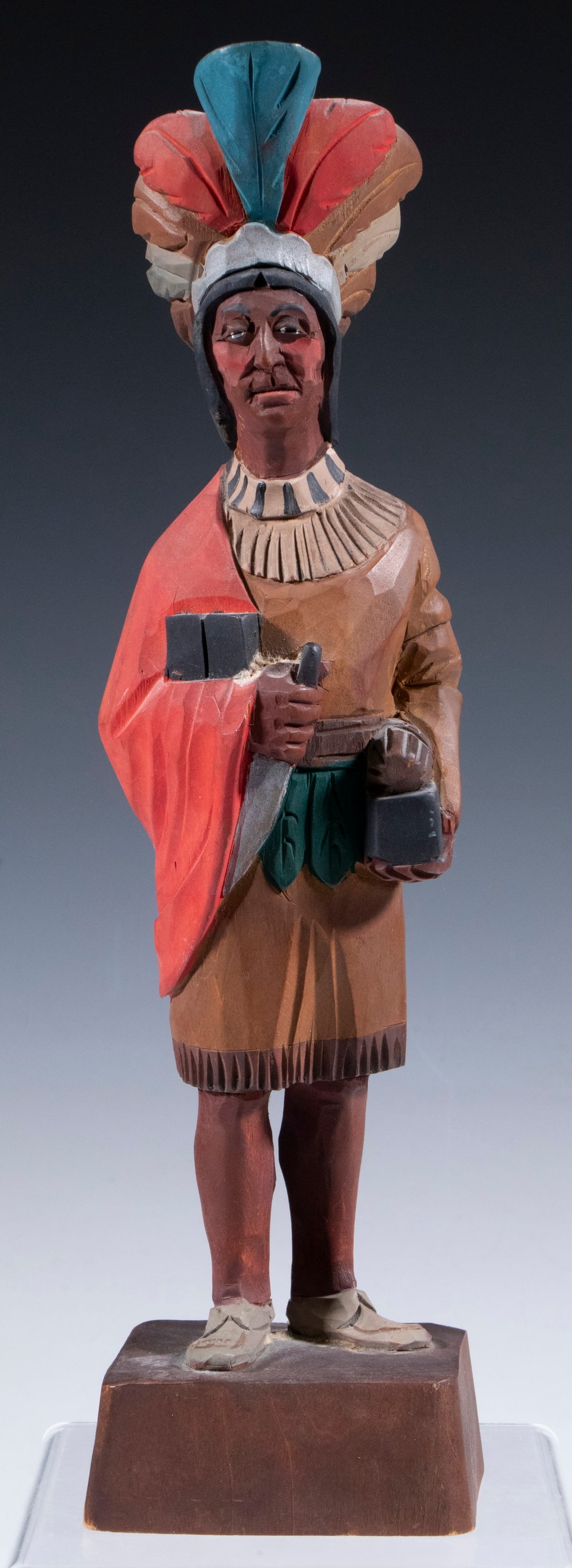 CARVED NATIVE AMERICAN FIGURE BY ELY HANNAH VERMONT: CARVED NATIVE AMERICAN FIGURE BY ELY HANNAH VERMONT Vintage Carved and Painted Wooden Sculpture, depicting a standing Native American. Signed on base. Height: 12 1/2 in. (31.8 cm.)