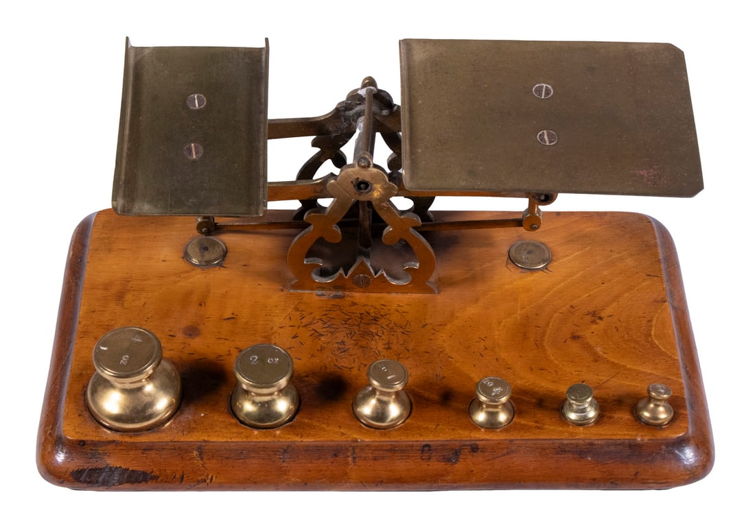 ENGLISH BRASS POSTAL SCALE WITH GRADUATED WEIGHTS: ENGLISH BRASS POSTAL SCALE WITH GRADUATED WEIGHTS Circa 1880 Letter Scale, set on a molded edge wooden base, with a set of six graduated brass weights up to 4-oz. 4 x 9 1/2 x 5 in. (10.2 x 24.1 x