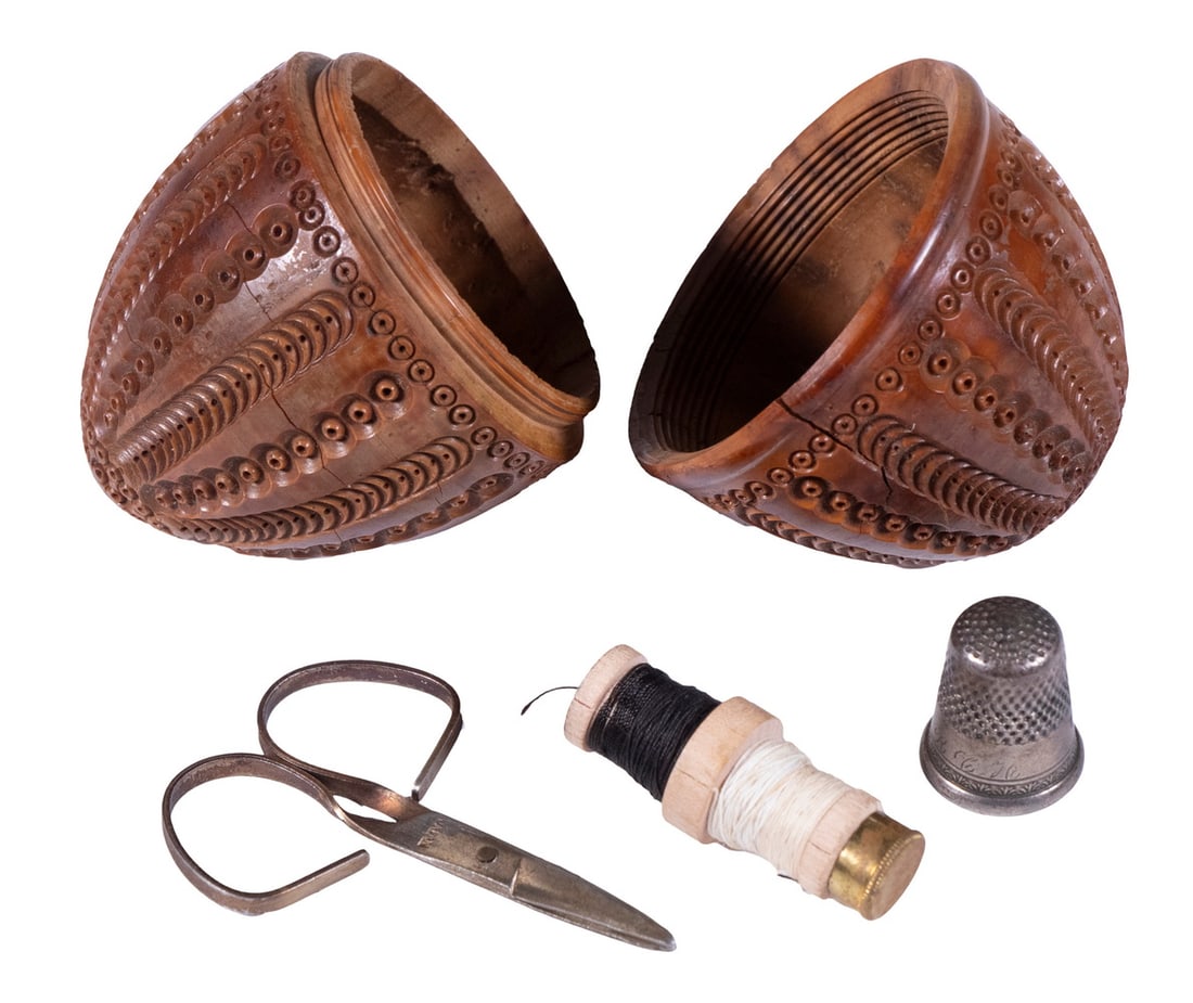 CARVED COQUILLA NUT SEWING EGG: CARVED COQUILLA NUT SEWING EGG19th c. Large Intricately Carved Coquilla Nut, containing a #7 thimble, small scissors and thread. Side crack.OS: 3 1/2 x 2 x 2 in. (8.9 x 5.1 x 5.1 cm.)