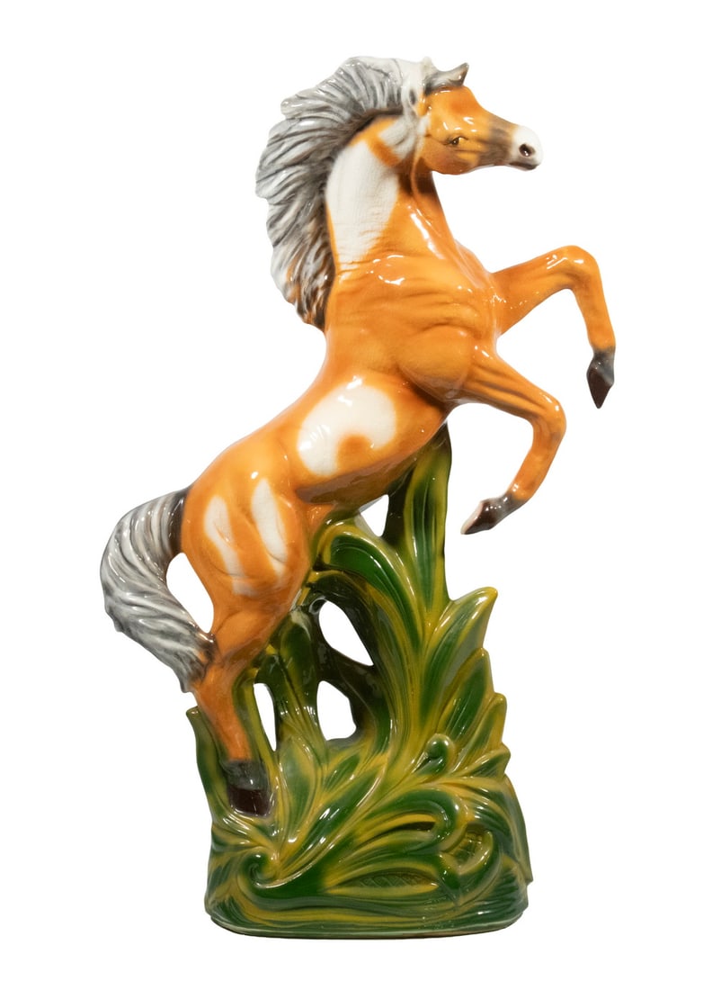 MID-CENTURY AMERICAN CERAMIC REARING HORSE FIGURE: MID-CENTURY AMERICAN CERAMIC REARING HORSE FIGURE Glazed ceramic sculpture of a rearing horse in ochre and cream tones with a white mane, set against a stylized green foliate base. Size: 27 1/2 x 16