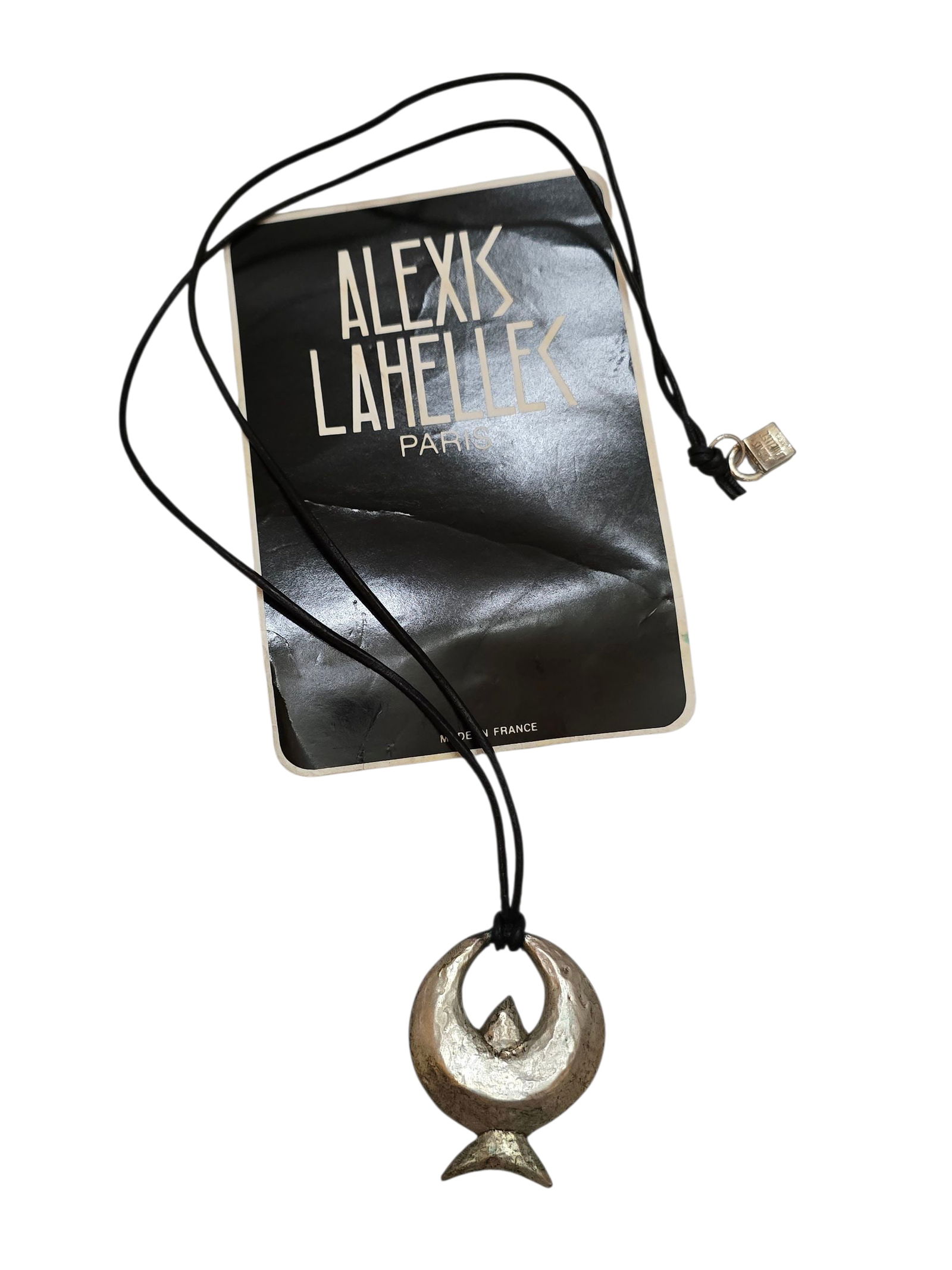 VINTAGE 80S RARE ALEXIS LAHELLEC PARIS NOS METALIZED PLASTIC SILVERTONE ABSTRACT CHARM ON LEATHER: VINTAGE 80S RARE ALEXIS LAHELLEC PARIS NOS METALIZED PLASTIC SILVERTONE ABSTRACT CHARM ON LEATHER CORD NECKLACE. 24", IN VERY GOOD CONDITION. HAS SIGNATURE LOCK AT BACK. WITH CARD. This is a New Old