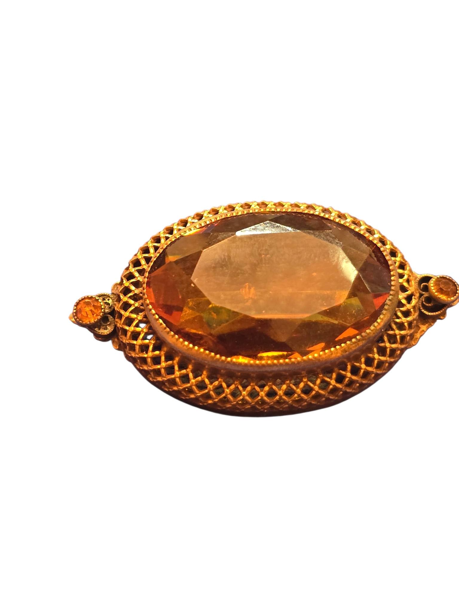 STUNNING FACETED PRONG SET LAYERED HEAVY BRASS BROOCH: STUNNING FACETED PRONG SET LAYERED HEAVY BRASS BROOCH. 2", THERE ARE SOME CHIPS TO THE BACK CENTER OF THE STONE, BEAUTIFULLY FACETED, SAW TOOTH BEZEL SETTING, FILIGREE LAYERED BORDER