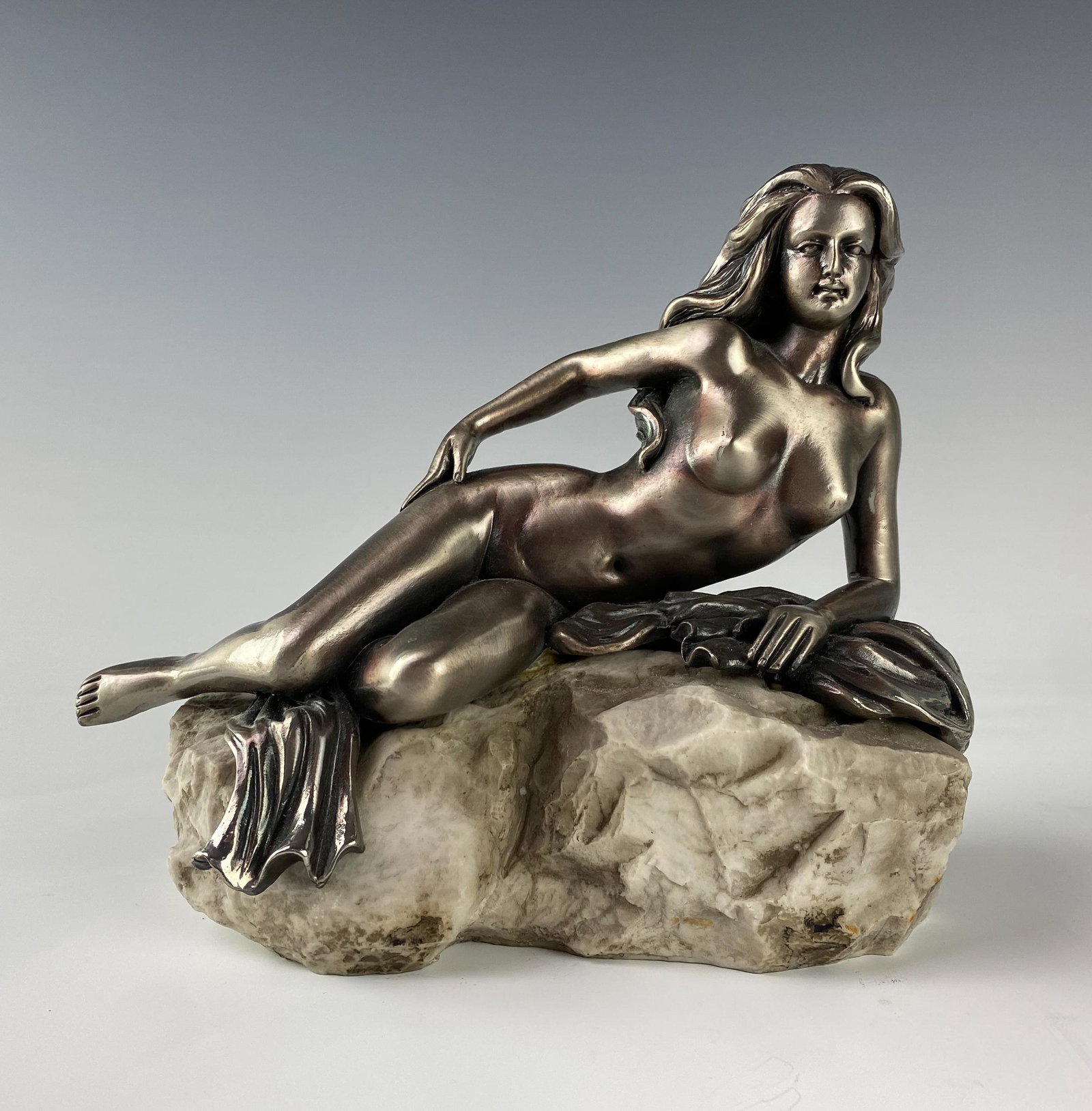 Nude Maiden on Rock Silver Erotica Resin Sculpture: Resin composition statue with silver tone finish modeled as a slender long haired nude female figure, in reclining pose, resting on a rock formation. Good estate fresh condition. Measures 6 1/2 in. x 