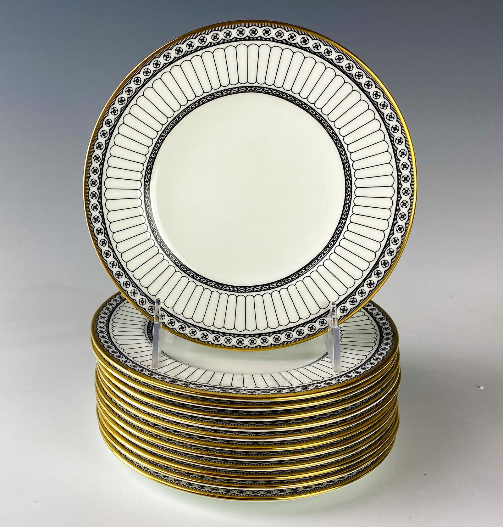 Wedgwood Bone China Colonnade Dessert Plate SET 12: Wedgwood (English). Black geometric line design with circles around border, rim with a gold trim. Pattern introduced 1960, retired 2004. Warm glazed finish. Signed with black urn stamp WEDGWOOD BONE C
