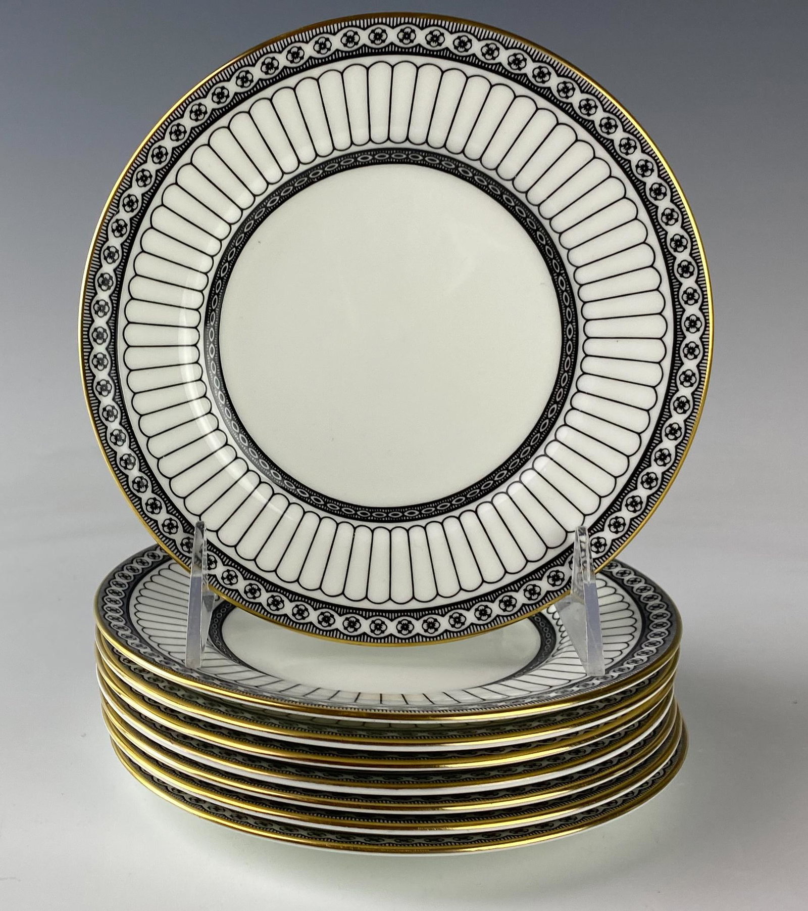 Wedgwood Bone China Colonnade Bread Butter Plates: Wedgwood (English). Set of eight. Black geometric line design with circles around border, rim with a gold trim. Pattern introduced 1960, retired 2004. Warm glazed finish. Signed with black urn stamp W