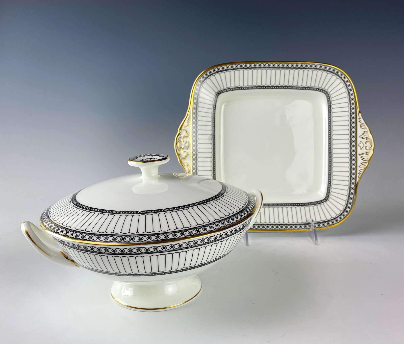 Wedgwood Bone China Colonnade Serving Pieces LOT: Wedgwood (English). Round covered vegetable dish and square handled cake plate. Black geometric line design with circles around border, rim with a gold trim. Pattern introduced 1960, retired 2004. War