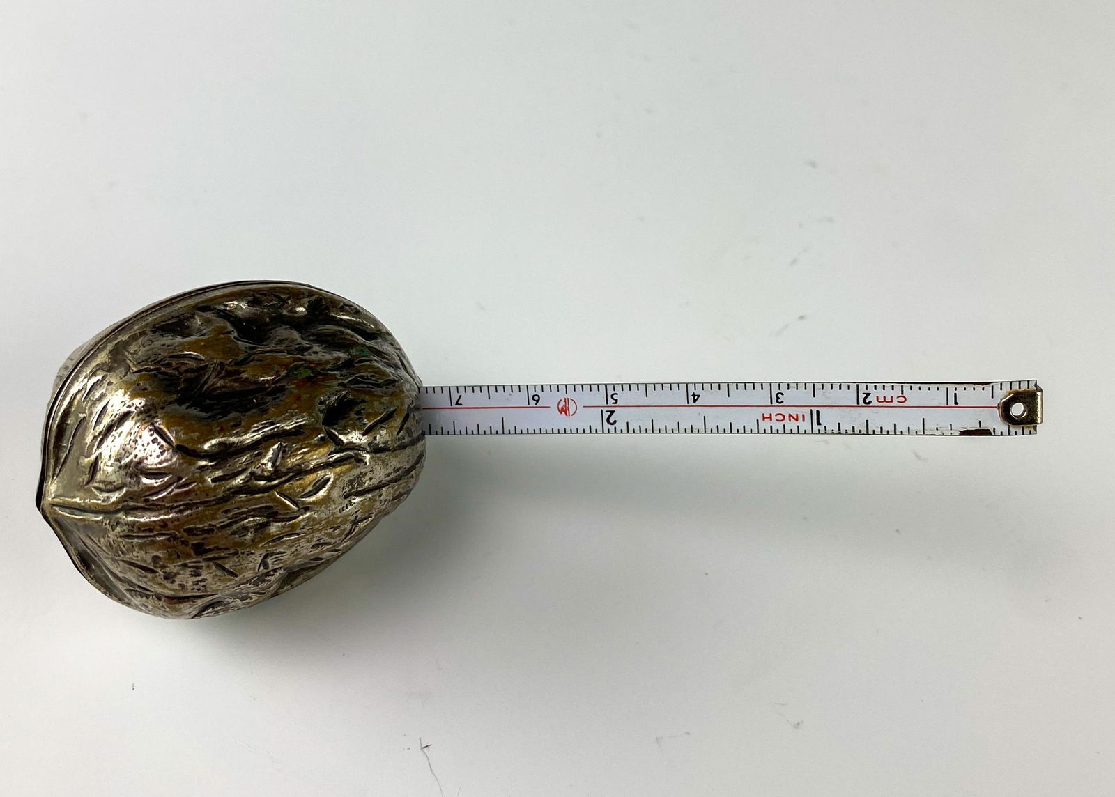 Victorian Antique Silver Plate Walnut Tape Measure: Well modeled silver plate walnut form with spring loaded tape measure cleverly housed with. Tape extends to approx. 38 inches. Aged patina intact. No monograms. Good estate fresh condition. No dents.