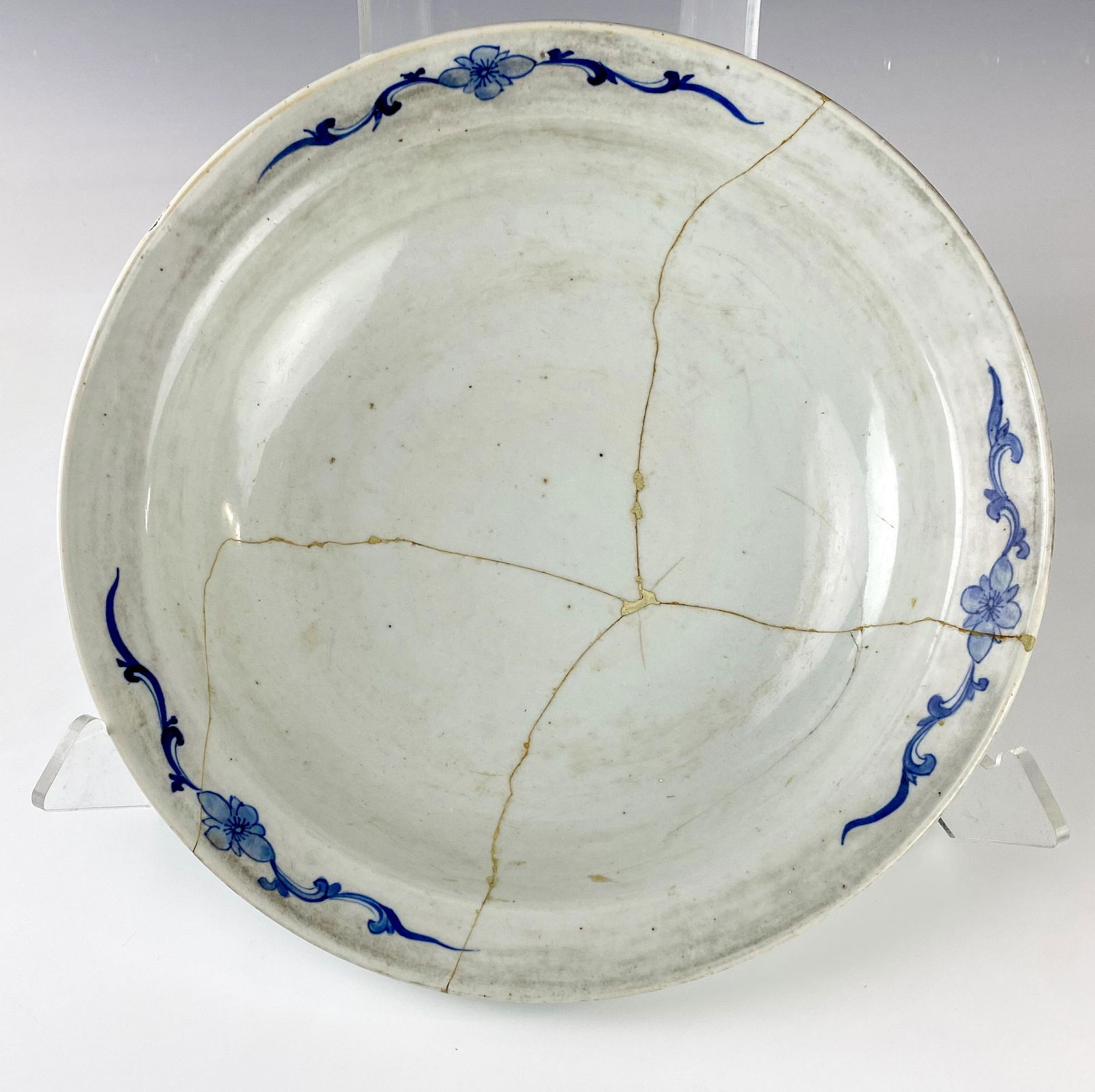 Chinese Antique Blue Bamboo Floral Porcelain Bowl: Large porcelain bowl with hand painted floral decorations around rim and bamboo designs to rim underside. Warm peppered appearance. Estate fresh condition. Crack lines and old staple repairs. Measures