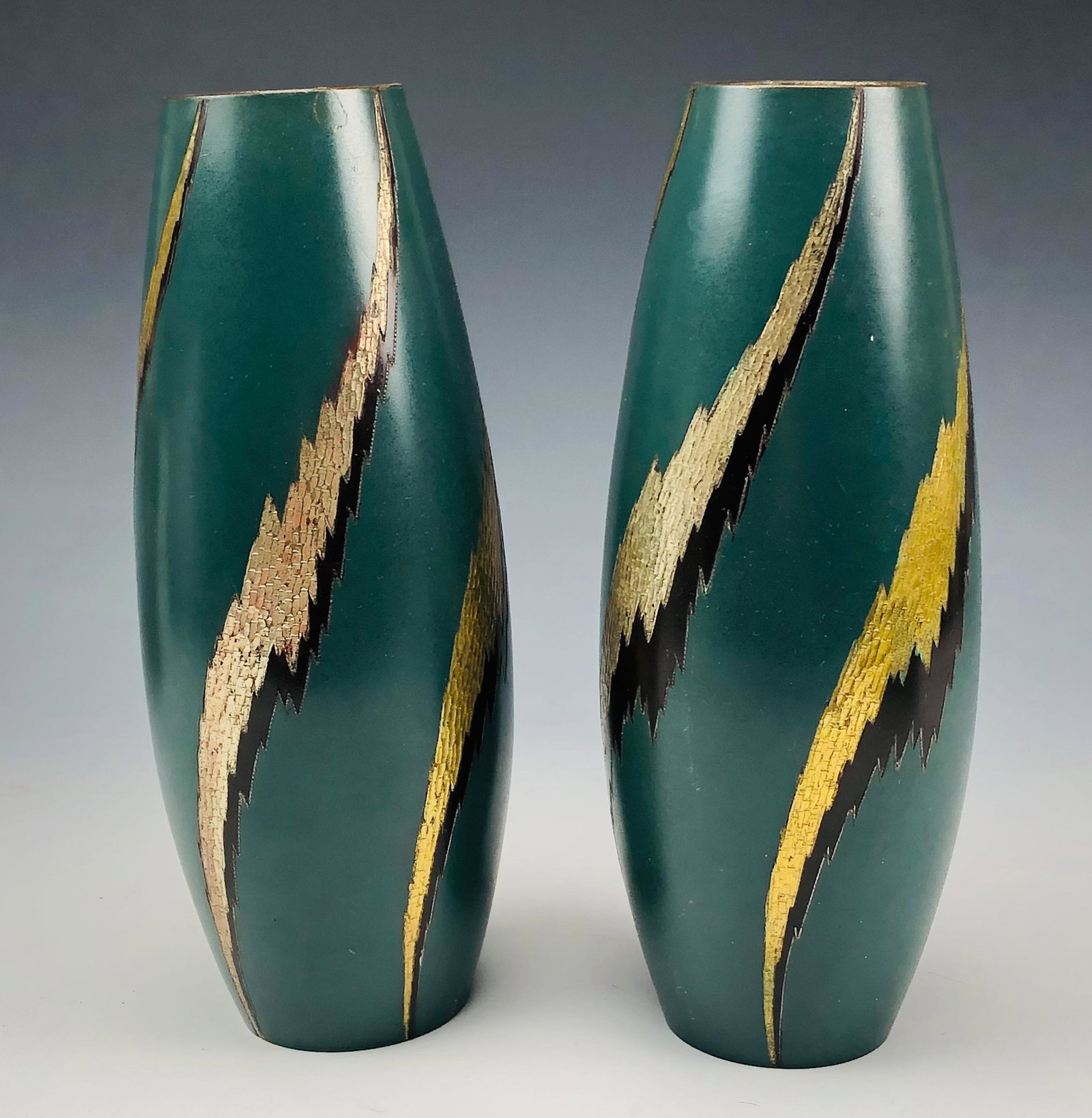 Signed Pr Japanese Enamel Gold Silver Tone Vases: Features a pair of Mid Century Modern Japanese Enameled Metallic Shelf Mantle Flower Vases. Of simple organic inspired forms. Bodies graced with silver and black toned streaks against a flat green gro