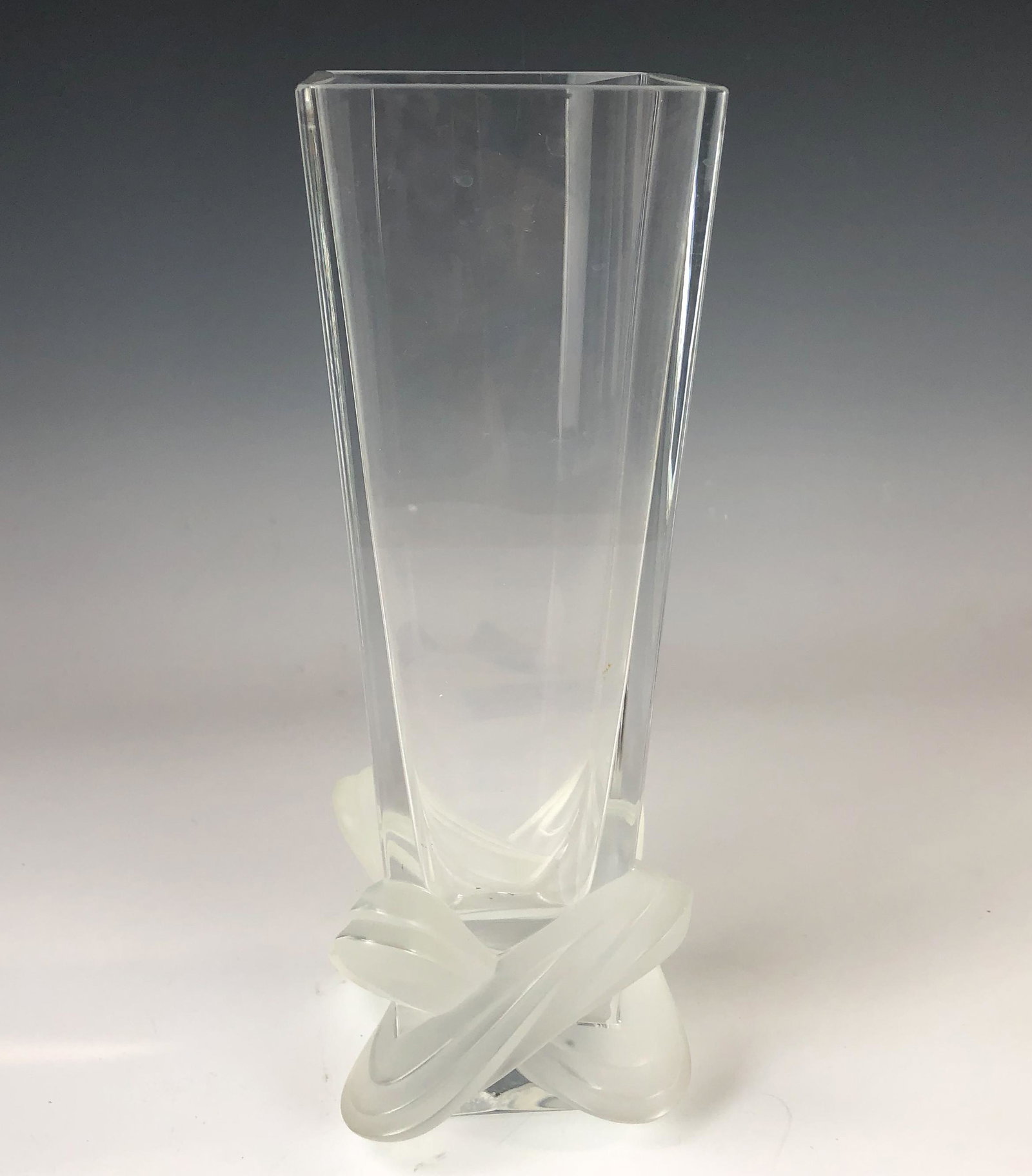 Lalique French Crystal Lucca Frosted Glass Vase: Features a graduated square elongated clear glass vase with frosted satin finish love knot, the symbol of everlasting love, on the base. Pattern Lucca was inspired by the Lucca region, known for their