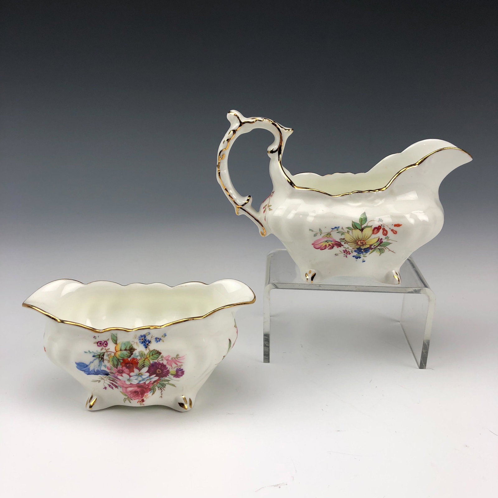 Hammersley Bone China Milk Creamer Sugar Bowl Set: Pretty English origin bone china creamer and sugar bowl by Hammersley. Both graced with brightly colored spring flowers against a white ground. Gold trimmed accents to the rim borders, handle and the 