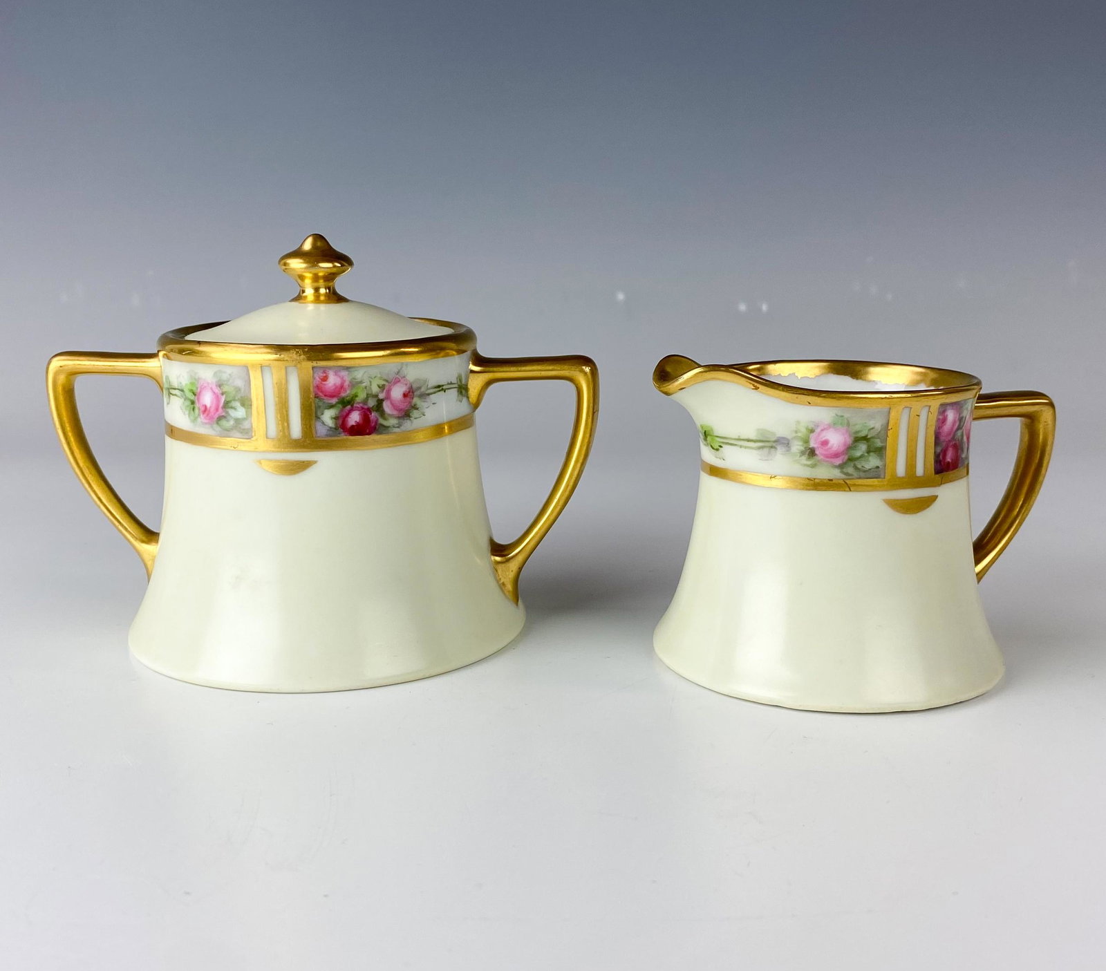 Limoges France Porcelain Milk Creamer & Sugar Bowl: Signed Limoges France Hand Painted Porcelain Milk Creamer & Lidded Sugar Pot Bowl. Red and pink rose floral designs grace the bodies on each against an off white ground. Rich gold painted accents nice
