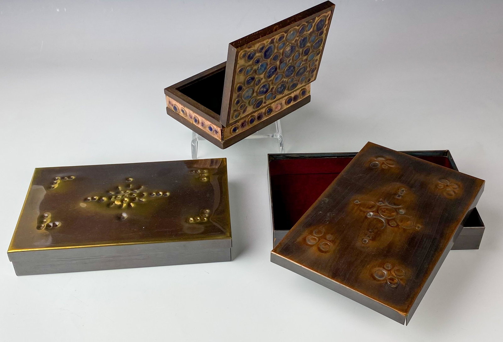 3 Copper Enamel Israel Hand Crafted Trinket Boxes: Painstakingly hand crafted in manner, all with a simplistic rectangular forms. The lids on 2 feature concave and convex inspired designs. One box graced with inlaid enamel accents all over, against a 