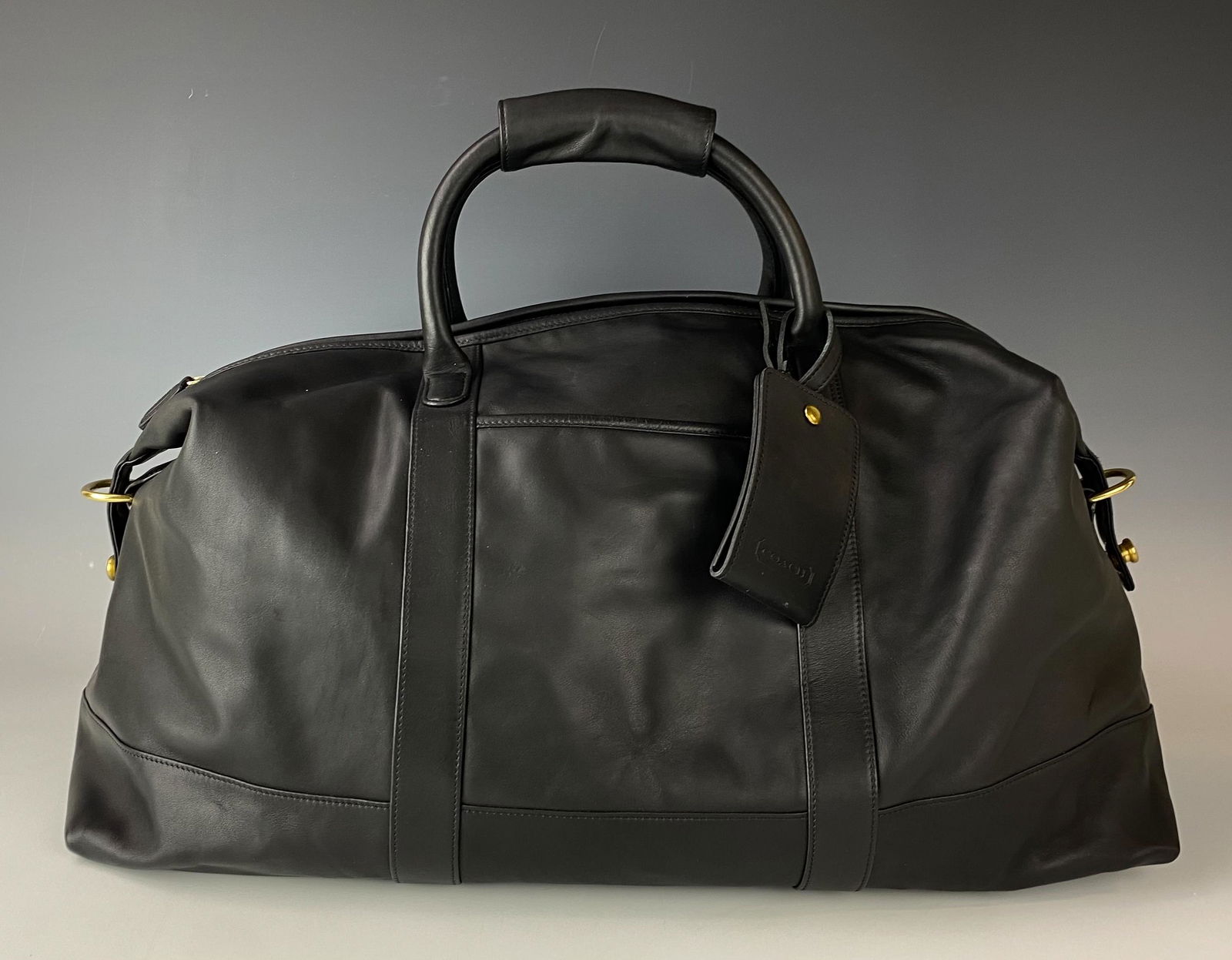 Coach BIS-0502 Black Leather Travel Shoulder Bag: Generously large and a nicely crafted black leather bag by Coach. A large zippered compartment on one side, within, a smaller zippered compartment on the opposite side. Solid sturdy strap handles with