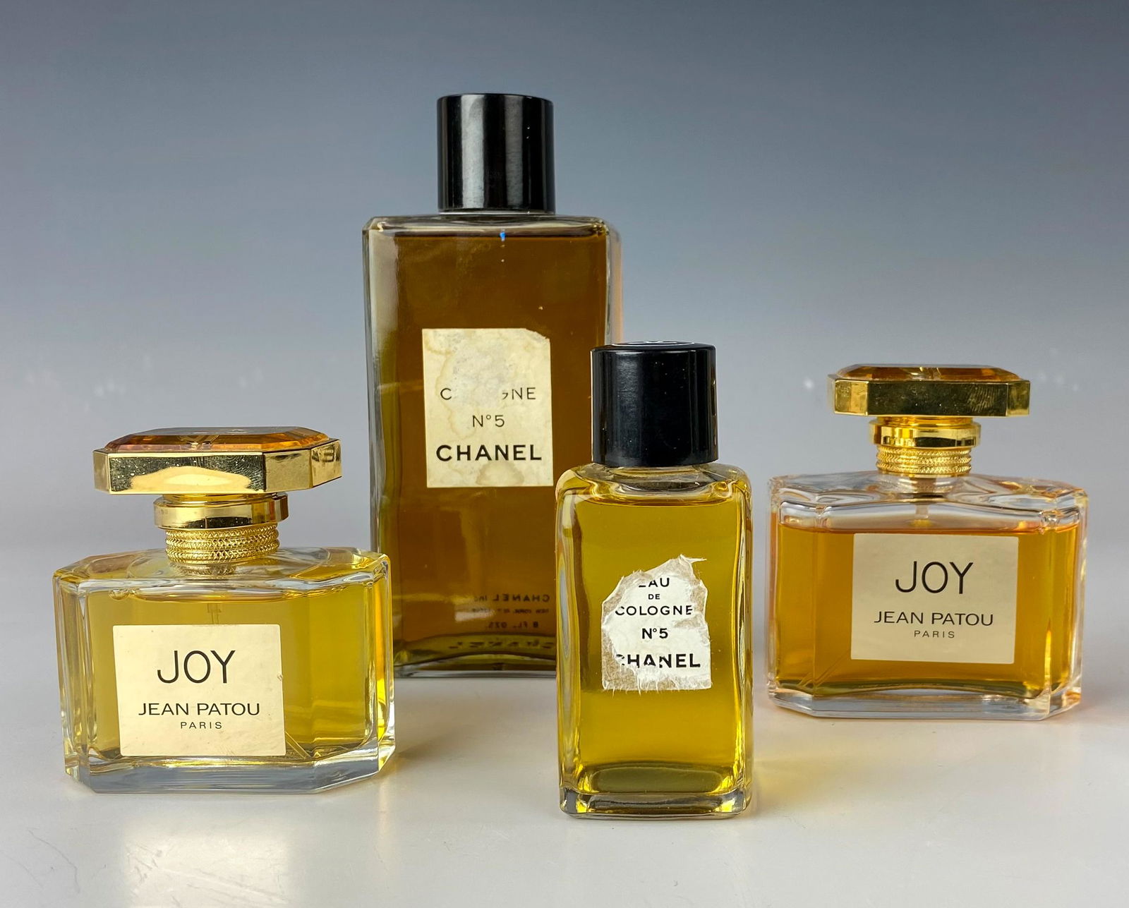 Estate Lot Joy & Chanel No 5 Scent Perfume Bottles: Included are the following bottles. 1 x Joy Jean Patou Paris 50ml bottle. 1 x Joy Jean Patou Paris 75ml bottle. 1 x Eau De Cologne Chanel no 5 8 fl oz bottle. Smaller Eau de Cologne Chanel no 5 bottle