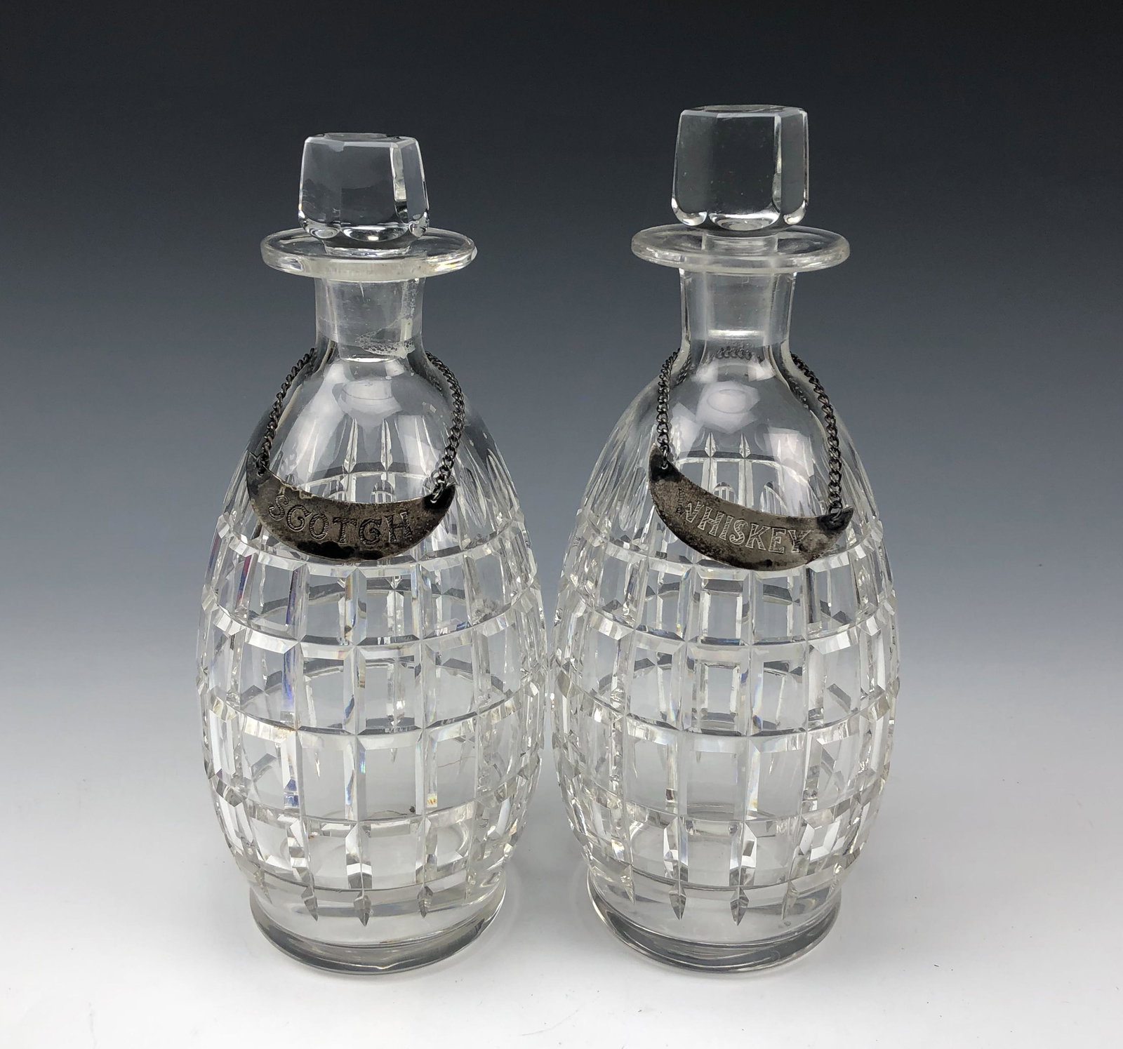 Pr Hawkes Cut Glass Bar Decanters w/ Sterling Tags: Features a pair of signed Hawkes cut glass bar barware alcohol liquor wine decanters. Bodies features a cut plaid pattern. Hexagonally shaped glass stoppers nicely fit into each opening at the mouth. 