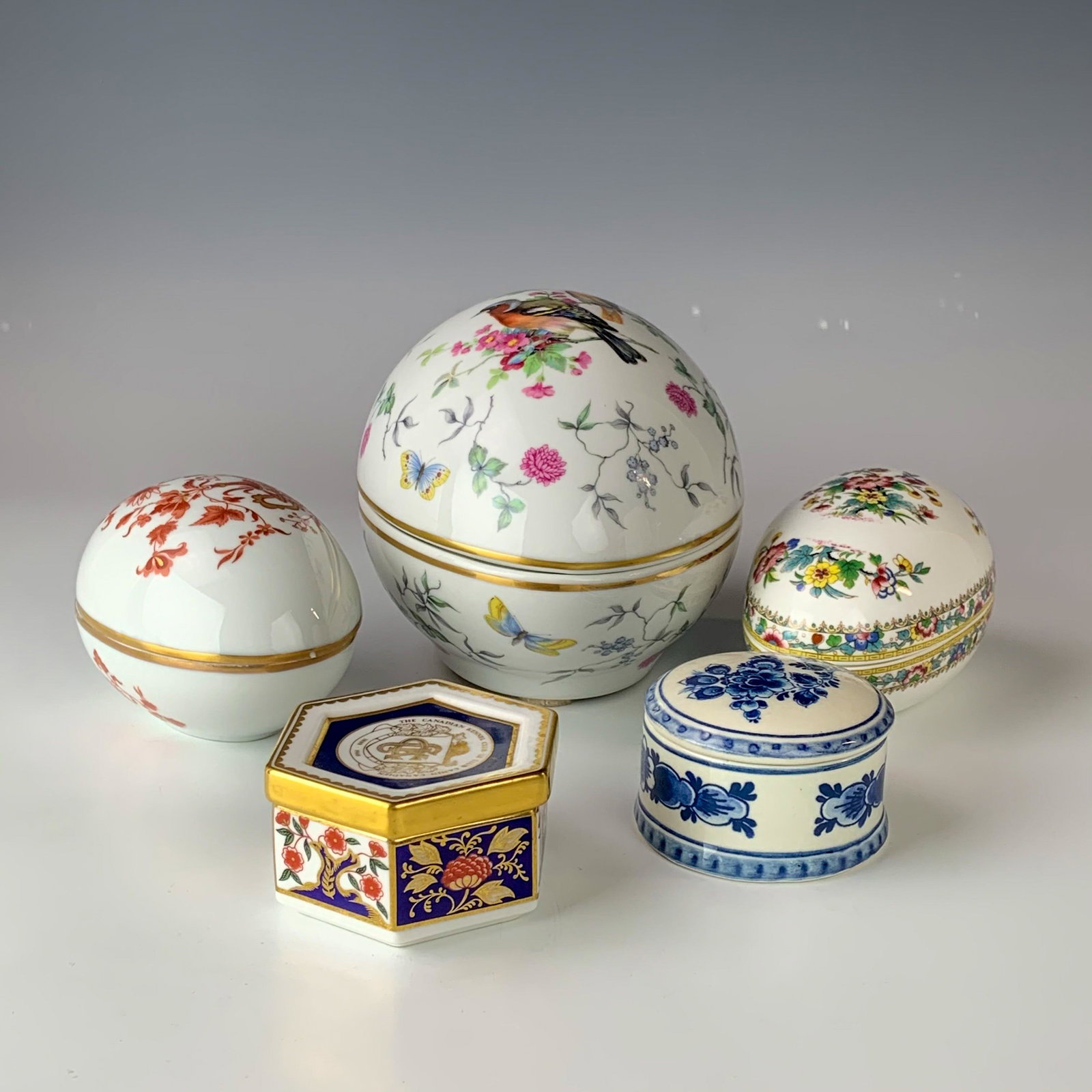 Estate Lot 5 Porcelain Trinket Jewelry Ring Boxes: A nice assortment of porcelain lidded jewelry trinket ring coin storage boxes. Three are egg shaped in manner, one is of rounded form, one is hexagonally shaped/ All graced with nature inspired scenes