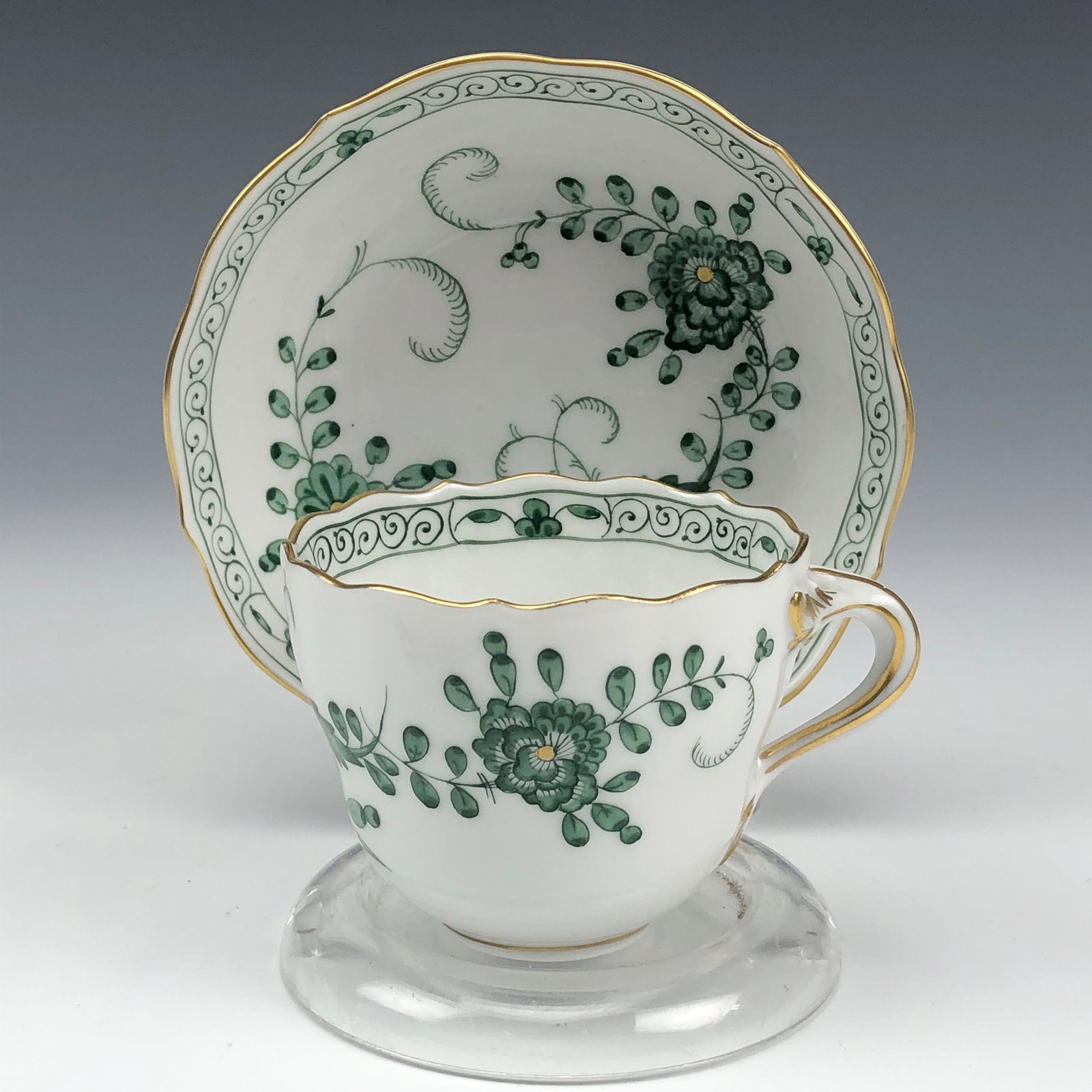 Meissen Porcelain Floral Demitasse Cup Saucer Set: Features a pretty hand painted floral pattern "Green Indian Flowers" manufactured by Meissen. Circa 20th Century. Both cup and saucer graced with a green flower, vine and leaf pattern, against a crisp