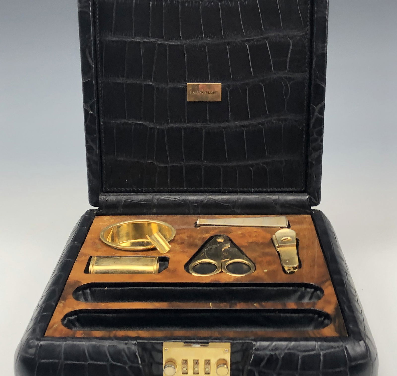 Harrison James Savinelli Black Leather Cigar Safe: Features a well crafted black reptile skin leather case safe box which houses several gold gilt cigar smoking tools within the slots assigned to each. 2 empty wells for cigar storage. Opens with the s
