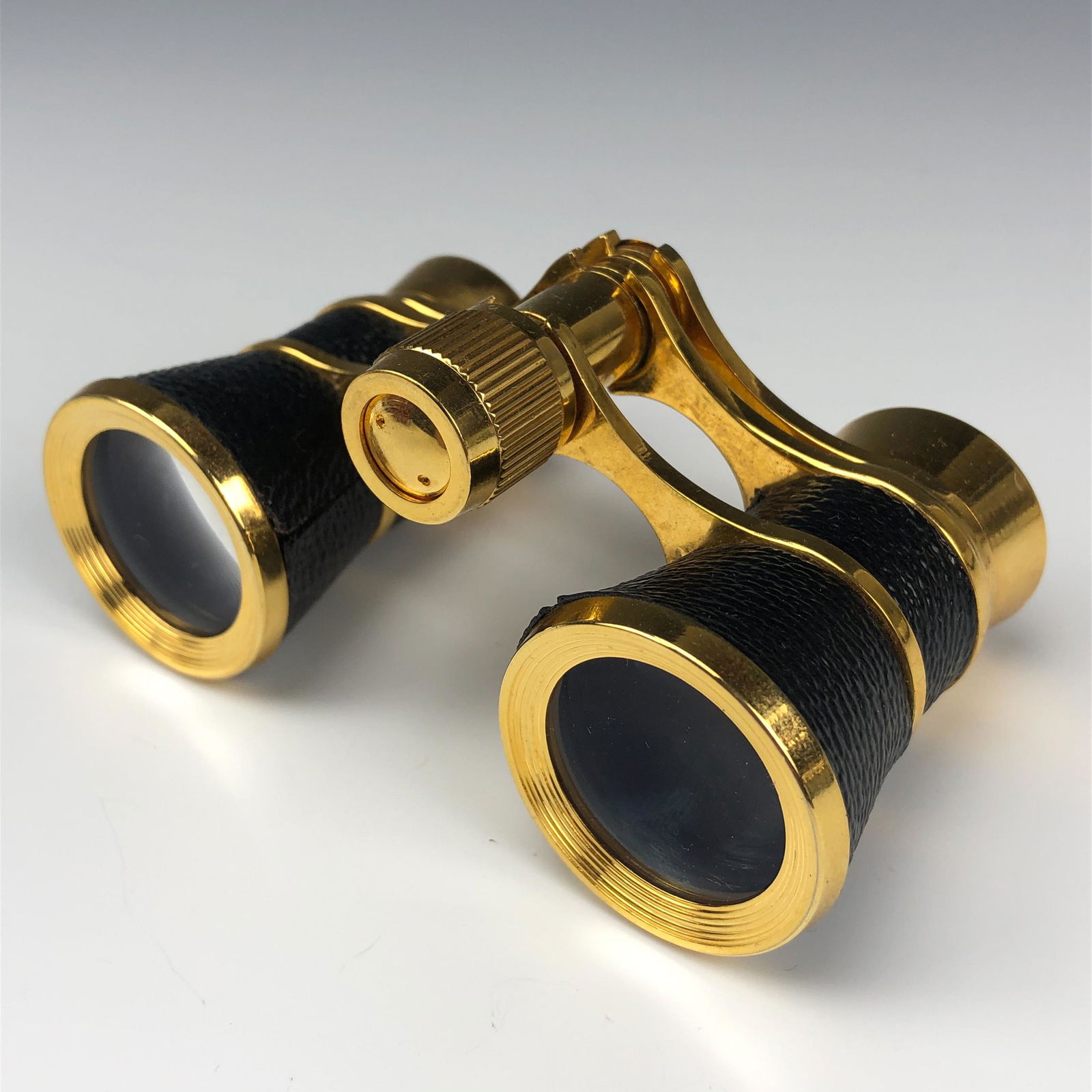 Gilt Brass w Black Leather Opera Theatre Glasses: Compactly well crafted and nicely modeled opera theatre glasses with black leather accents. Crisp visibility with nice magnification. No dust. fungus or dirt in either lens. Wheel is tight but moves s